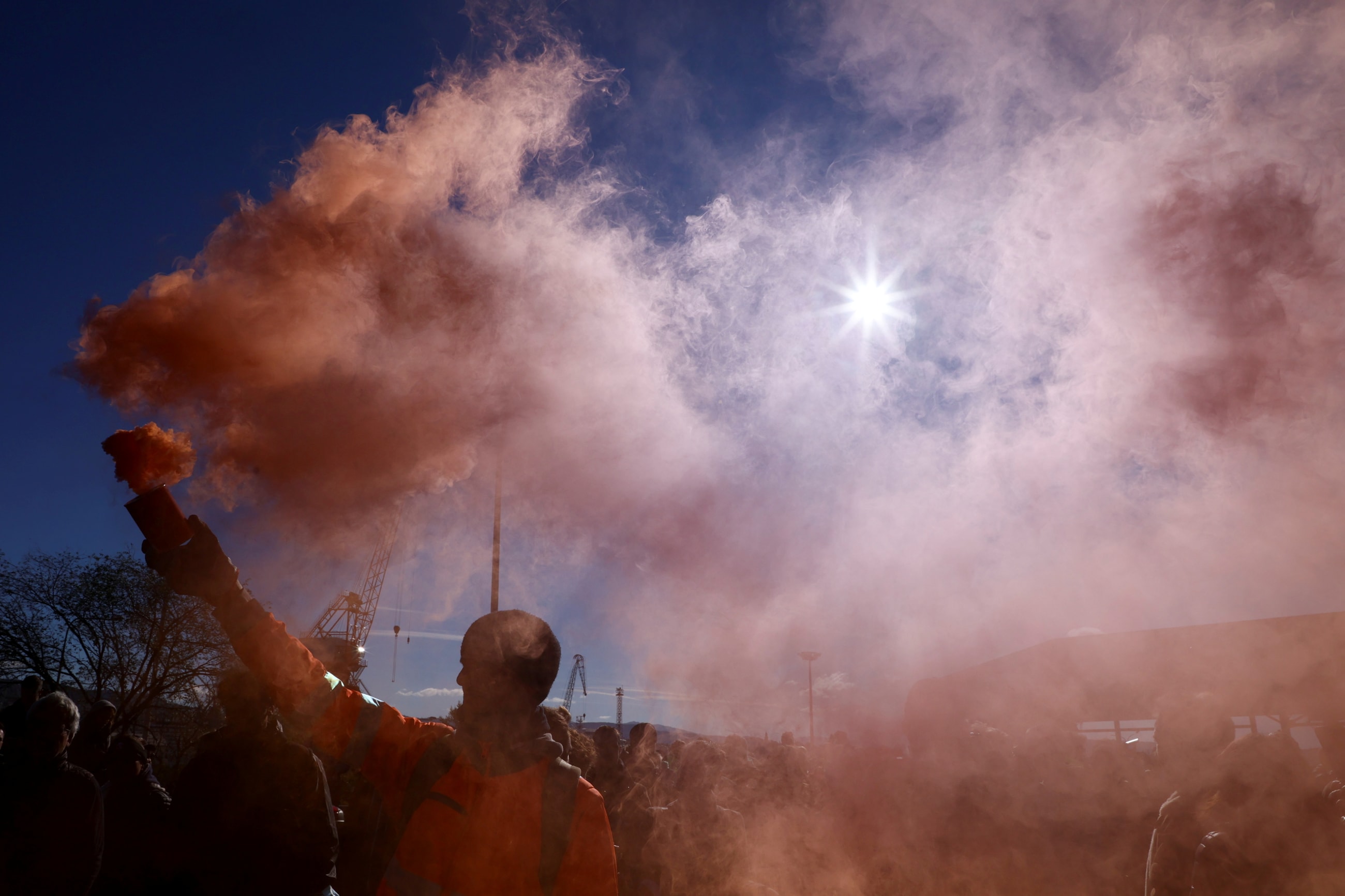 A person holds a flare as port workers gather outside the entrance of the major port of Trieste to protest against the implementation of the COVID-19 health pass, the Green Pass, in the workplace, in Trieste, Italy, October 15, 2021.