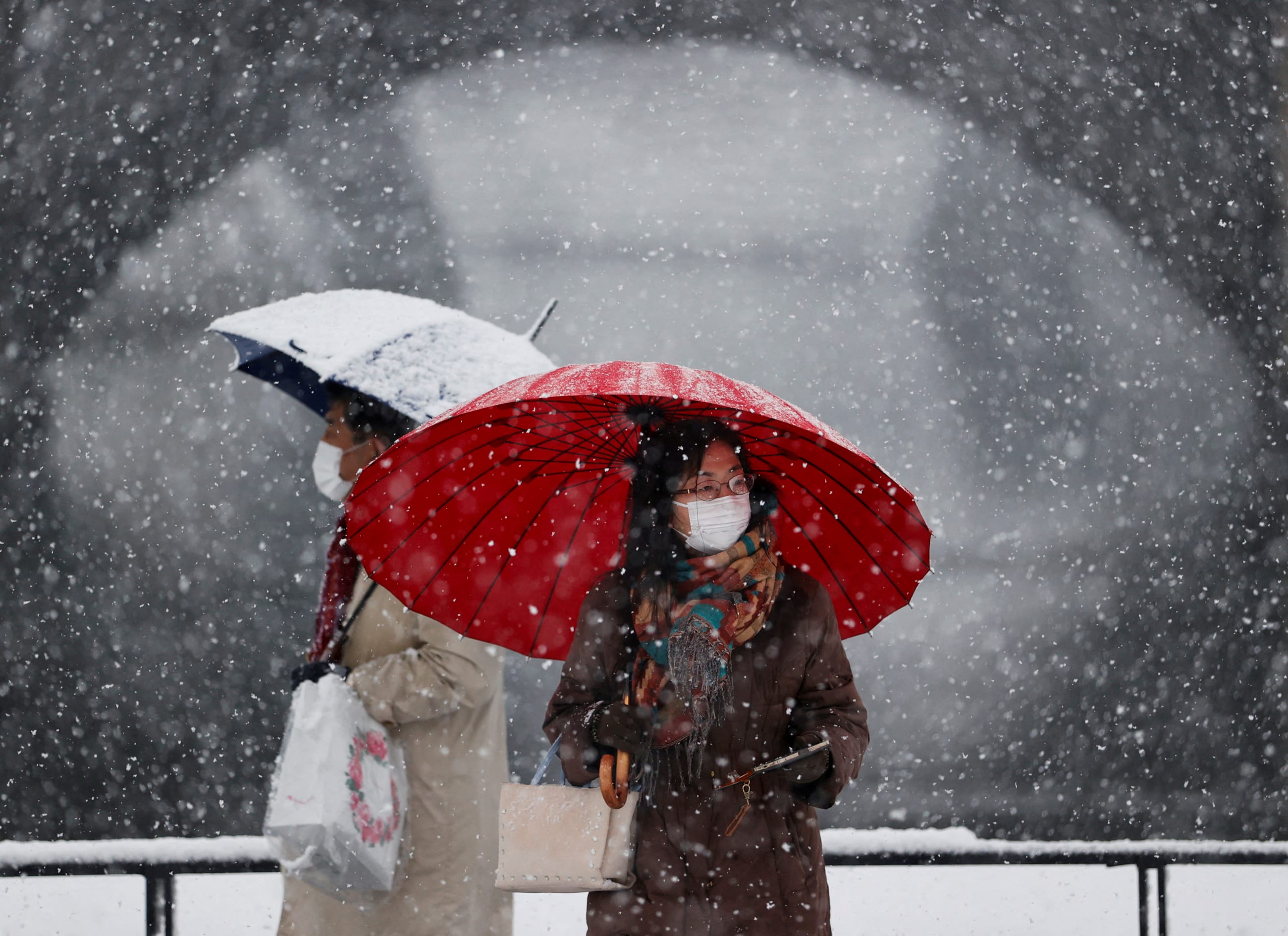 People wearing protective face masks visit the snow-covered Imperial Palace, amid the coronavirus disease (COVID-19) pandemic, in Tokyo, Japan January 6, 2022.