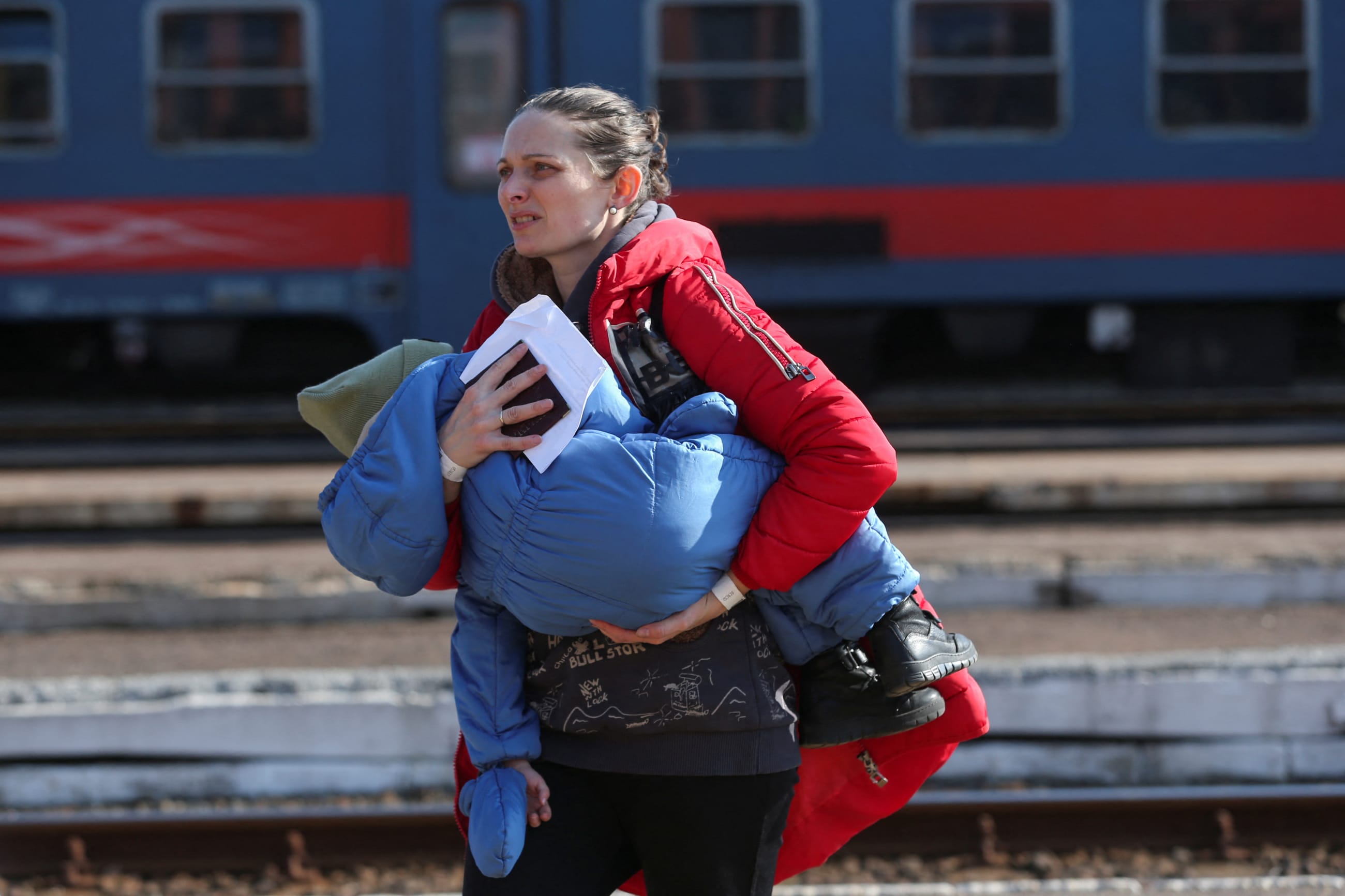 A woman fleeing Russia's invasion of Ukraine carries a child at the train station in Zahony, Hungary on March 6, 2022.