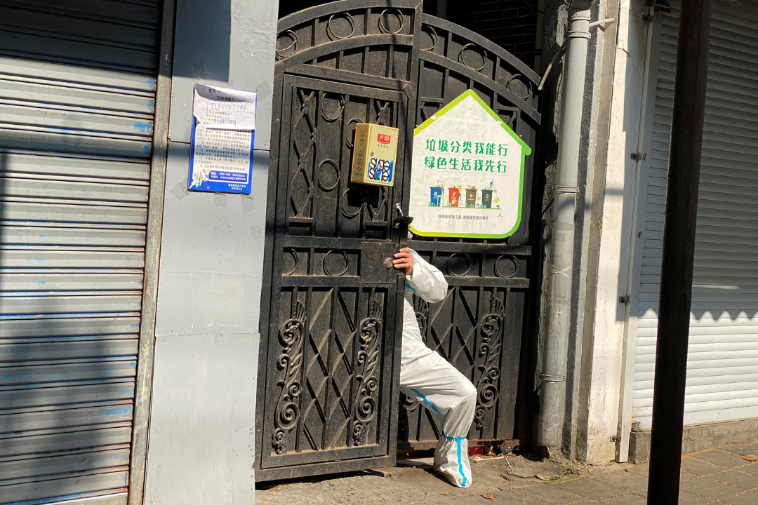 A person in a protective suit squeezes through a locked gate of a residential compound, during a COVID-19 outbreak and lockdown in Shanghai, China, on April 21, 2022.