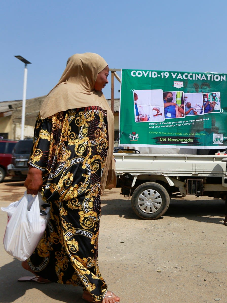 A woman walks past a COVID-19 campaign truck during a mass vaccination exercise at Wuse market in Abuja, Nigeria, on January 26, 2022.