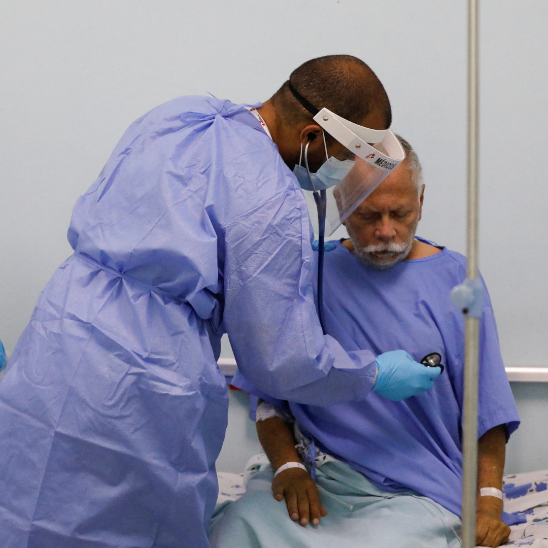 A physician with Doctors Without Borders (MSF) places his stethoscope on the chest of hospital patient Marco Vargas, who has COVID, in Caracas, Venezuela, on February 1, 2022.