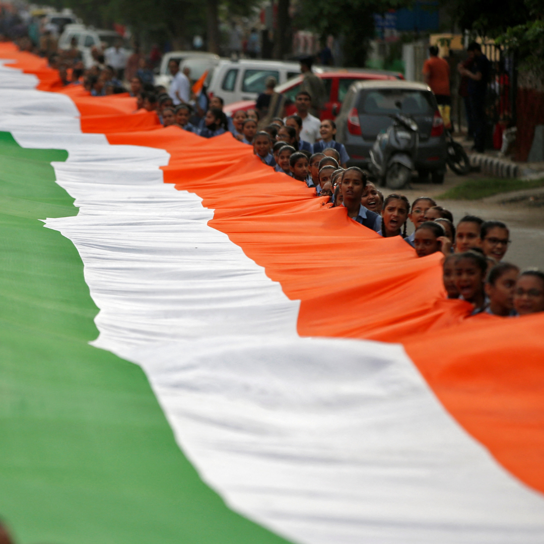 Students hold a giant Indian national flag with green, white and orange stripes, during celebrations commemorating 75 years of India's Independence, in Ahmedabad, India, August 8, 2022. 