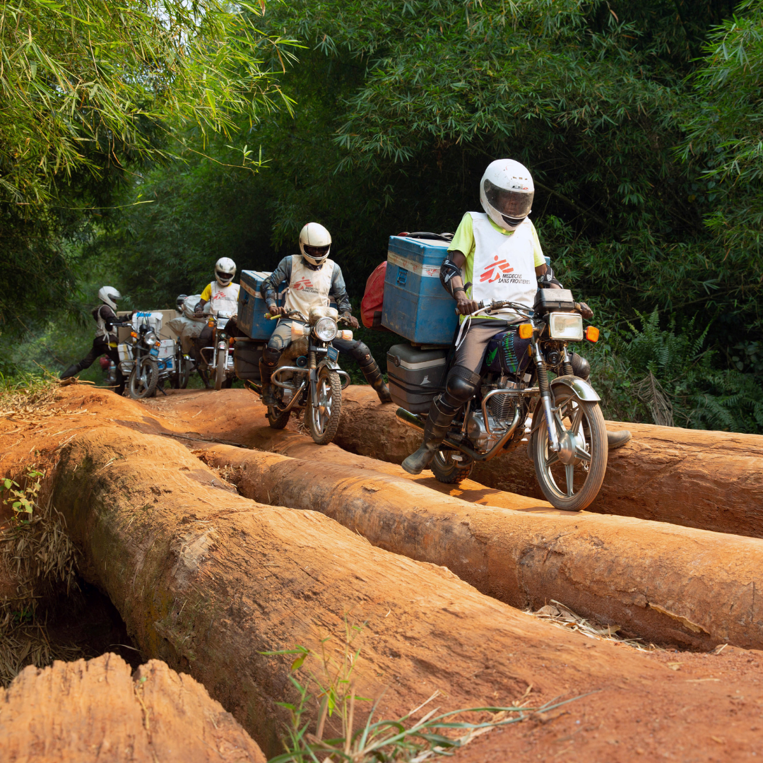 A motorcycle convoy carrying measles vaccines for the NGO Doctors Without Borders crosses a log bridge in Mongala Province, in the Democratic Republic of Congo, on February 27, 2020.