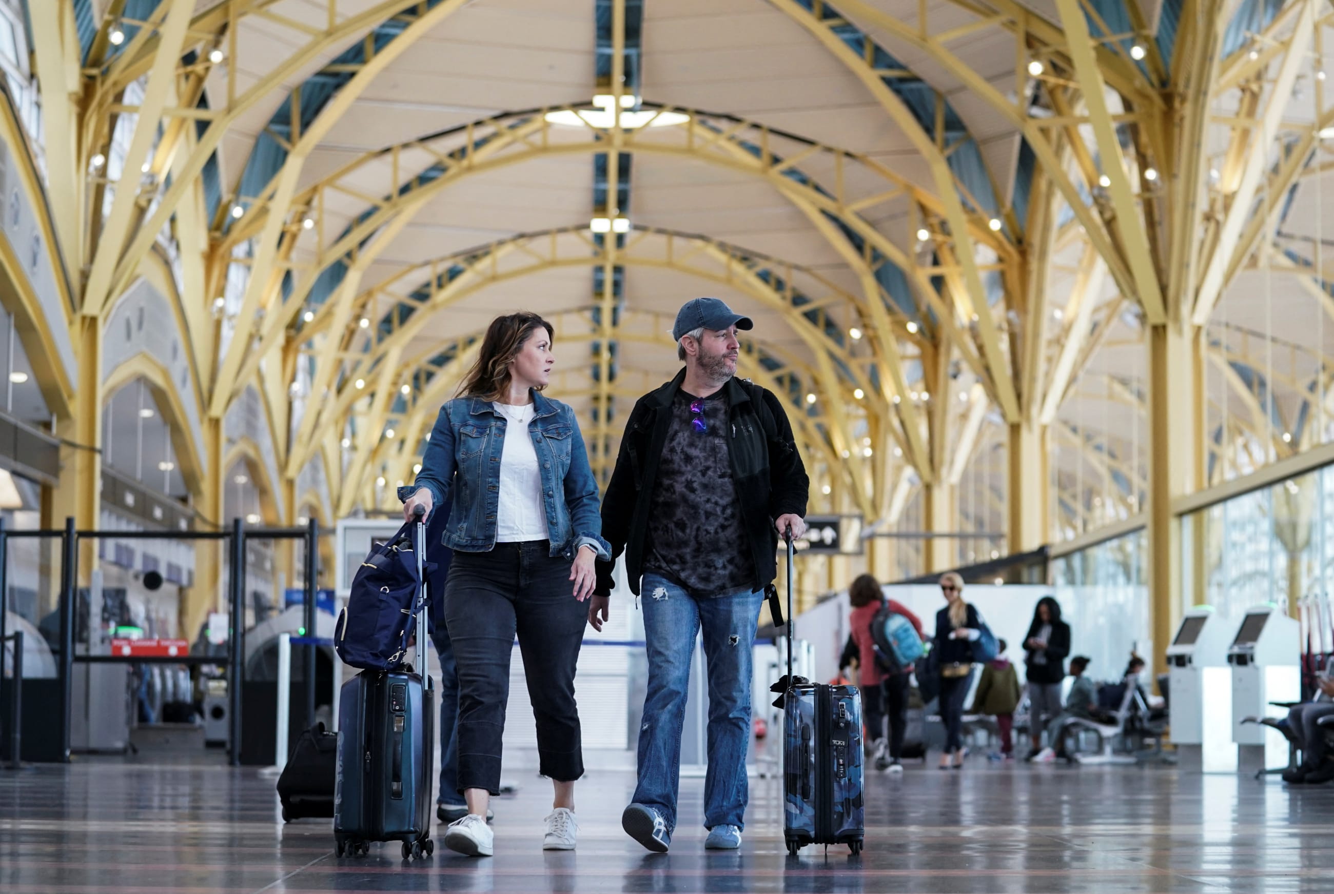 An unmasked couple makes their way through Ronald Reagan Washington National Airport after the Biden administration announced it would no longer enforce a mask mandate, on April 19, 2022.
