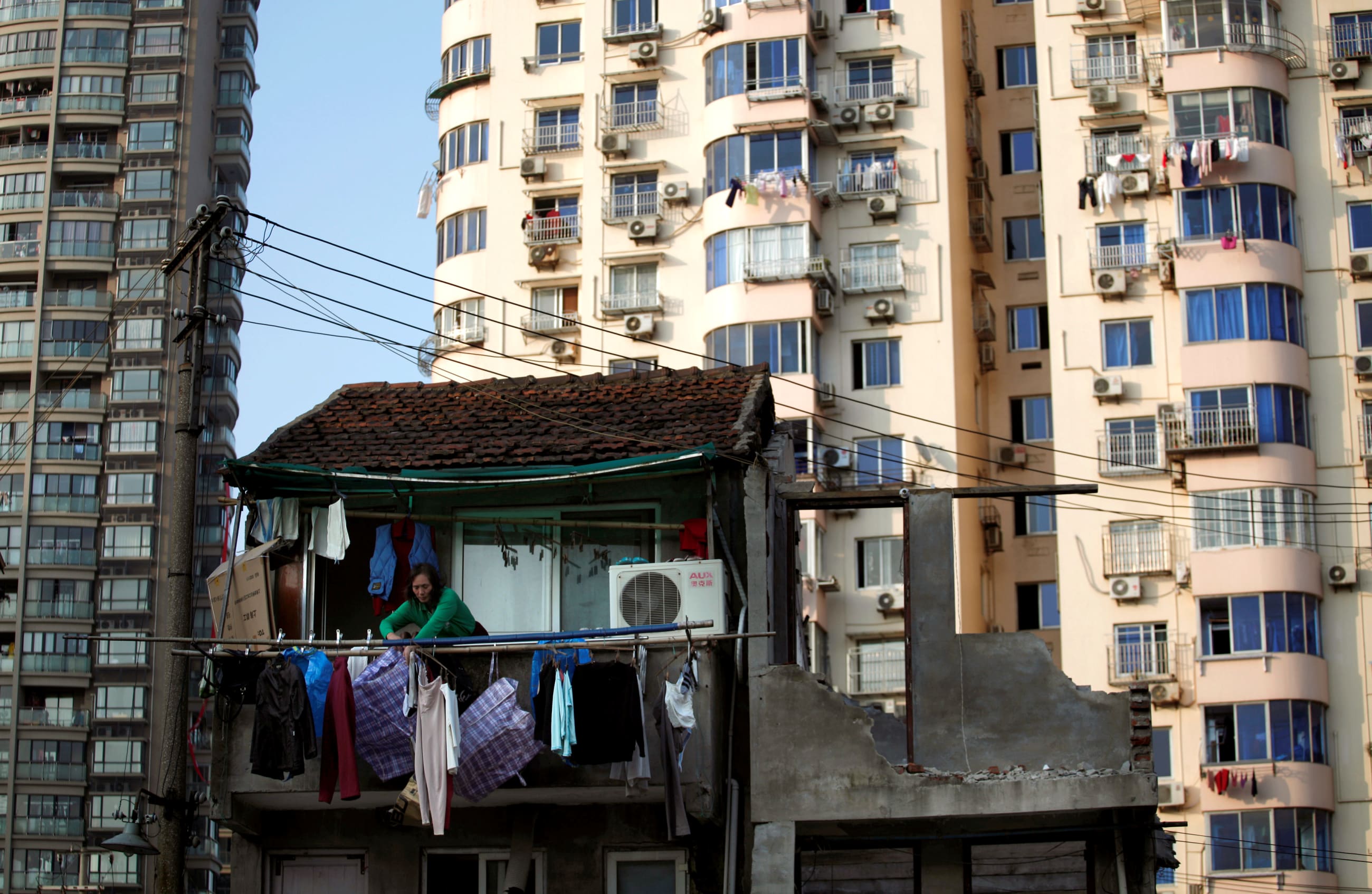 A woman stands at the balcony of her house, which will be demolished to build new apartments in downtown Shanghai, China, on December 1, 2010.
