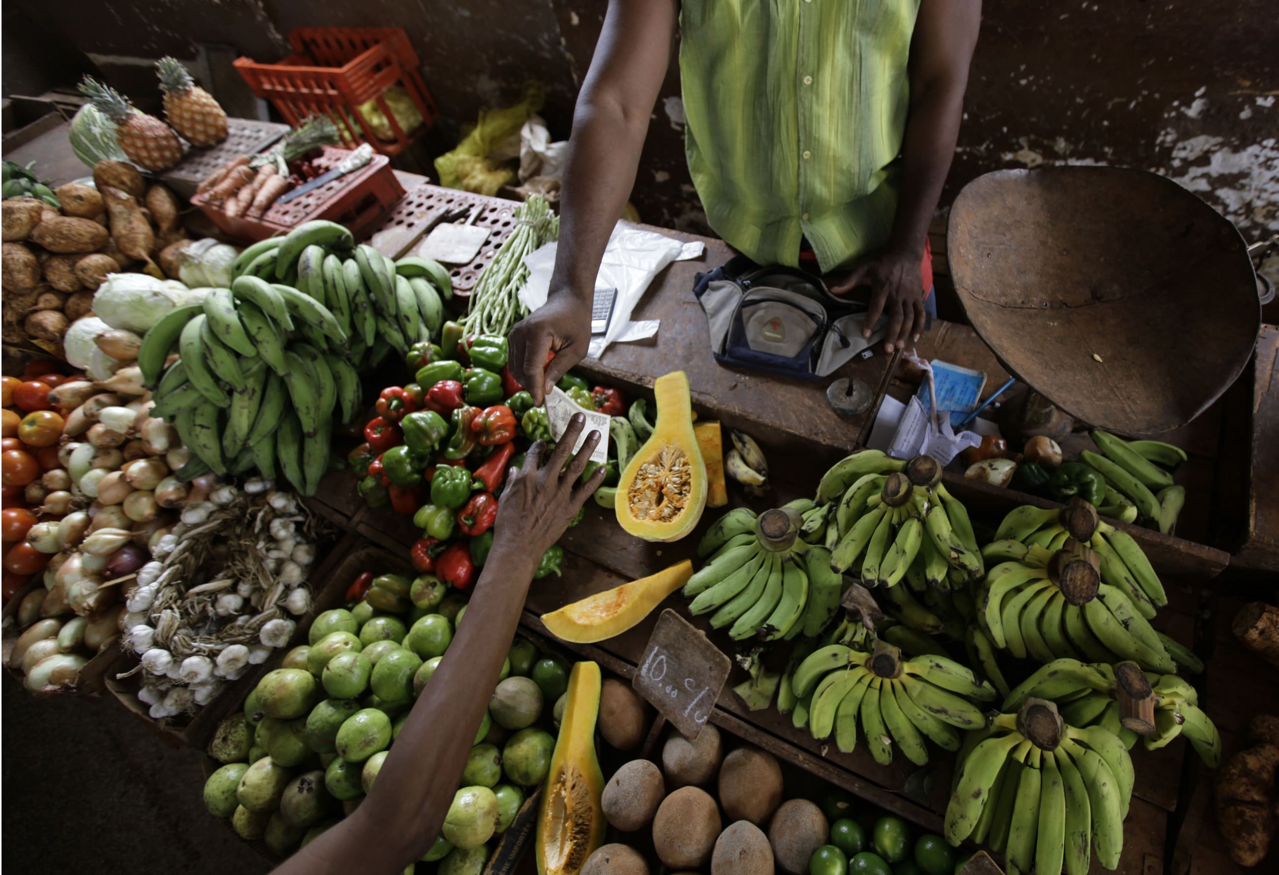 A vendor sells vegetables at a food market.