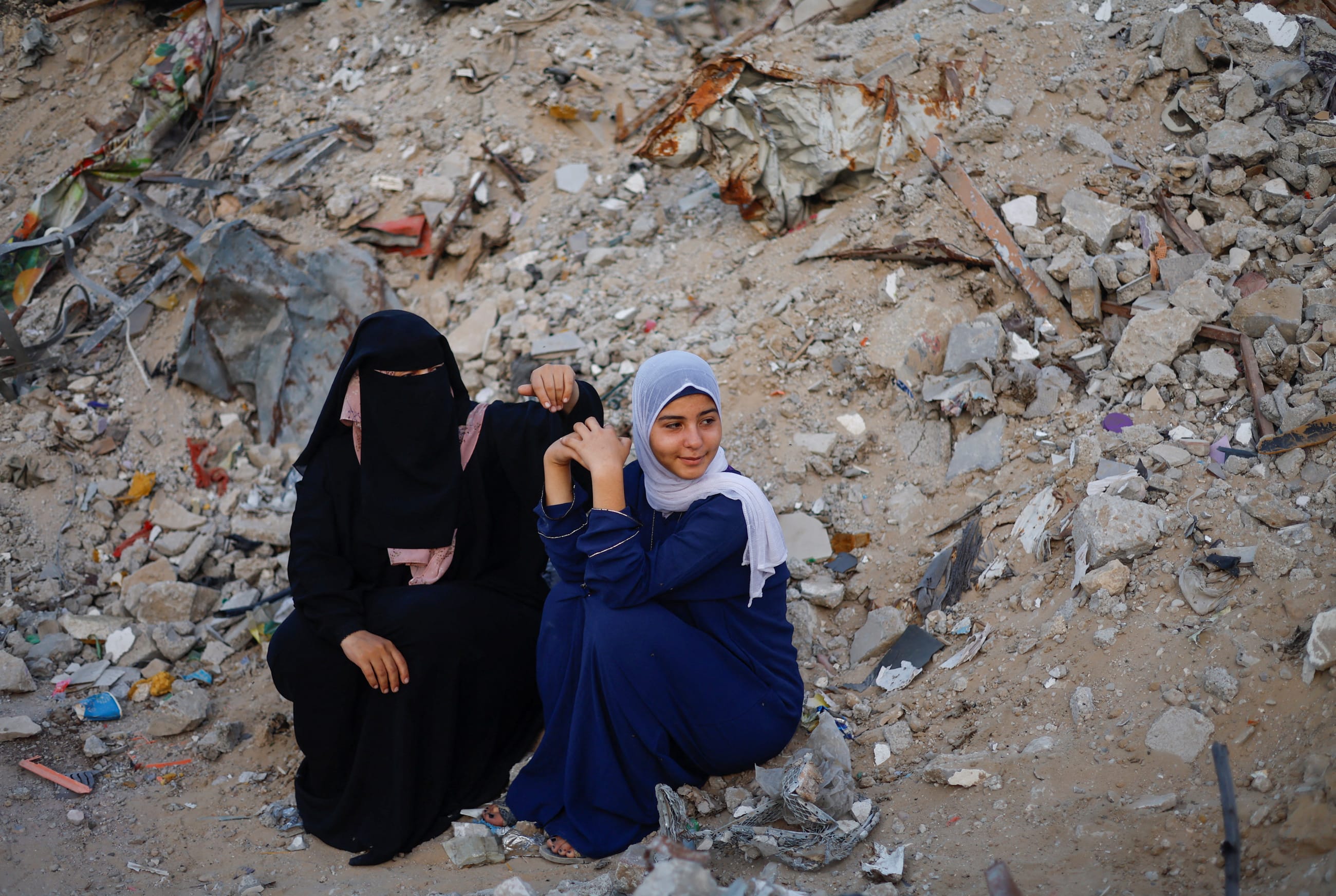 Palestinian women look on as others hold Eid al-Adha prayers by the ruins of the Al-Rahma mosque destroyed by Israeli air strikes.