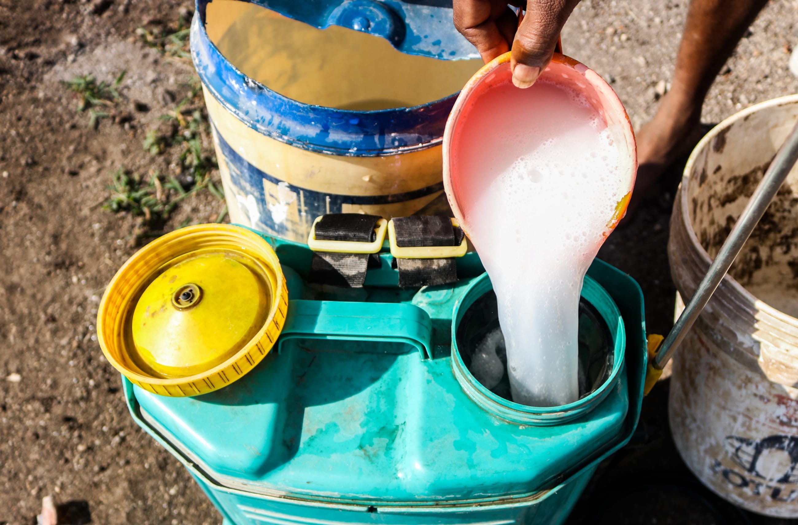 A farmer preparing a mixture of potent chemical pesticides to protect his vegetables.