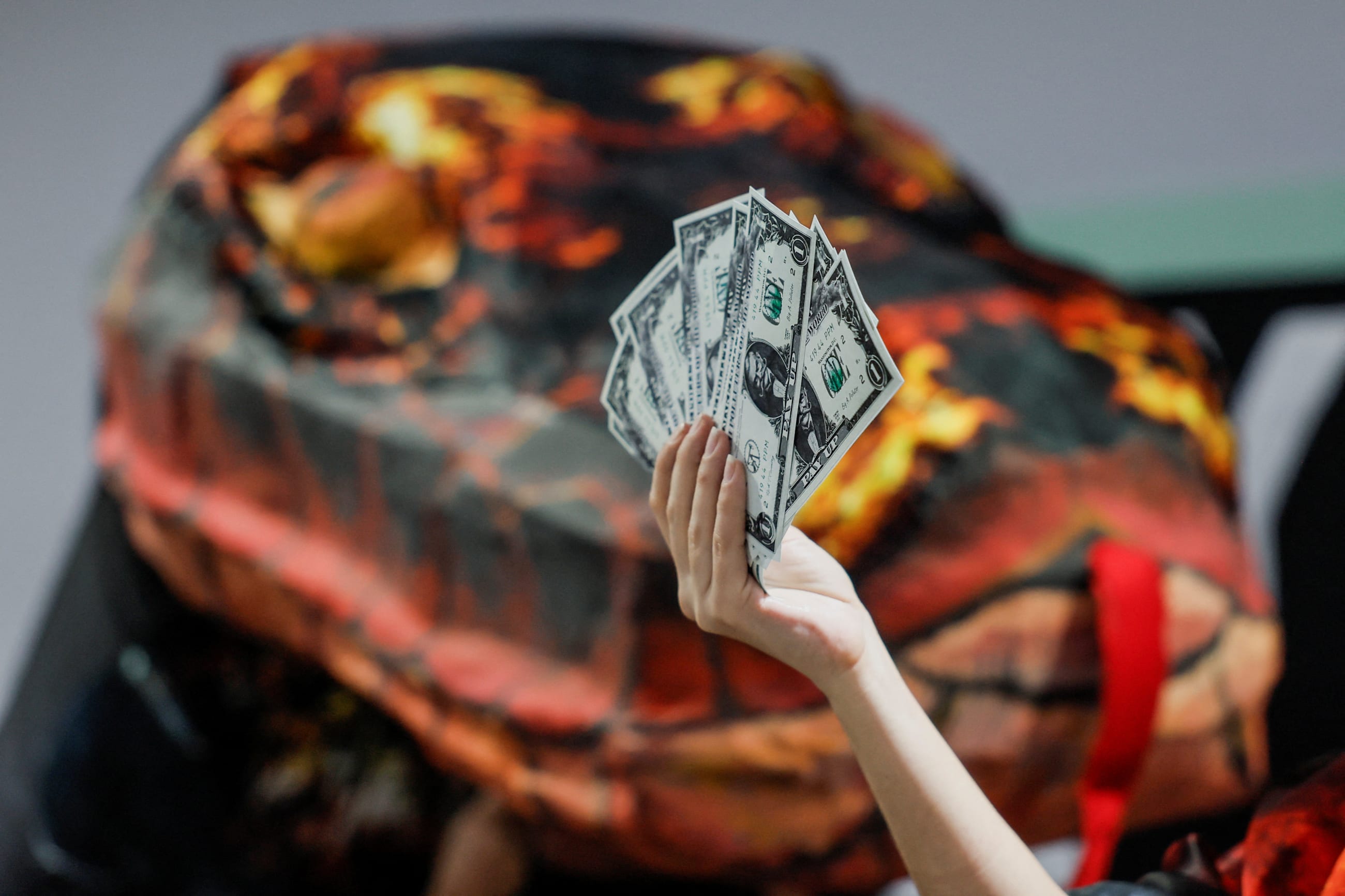 An activist holds up fake currency bills as she participates in a protest action during the United Nations climate change conference COP29 in Baku, Azerbaijan November 20, 2024.