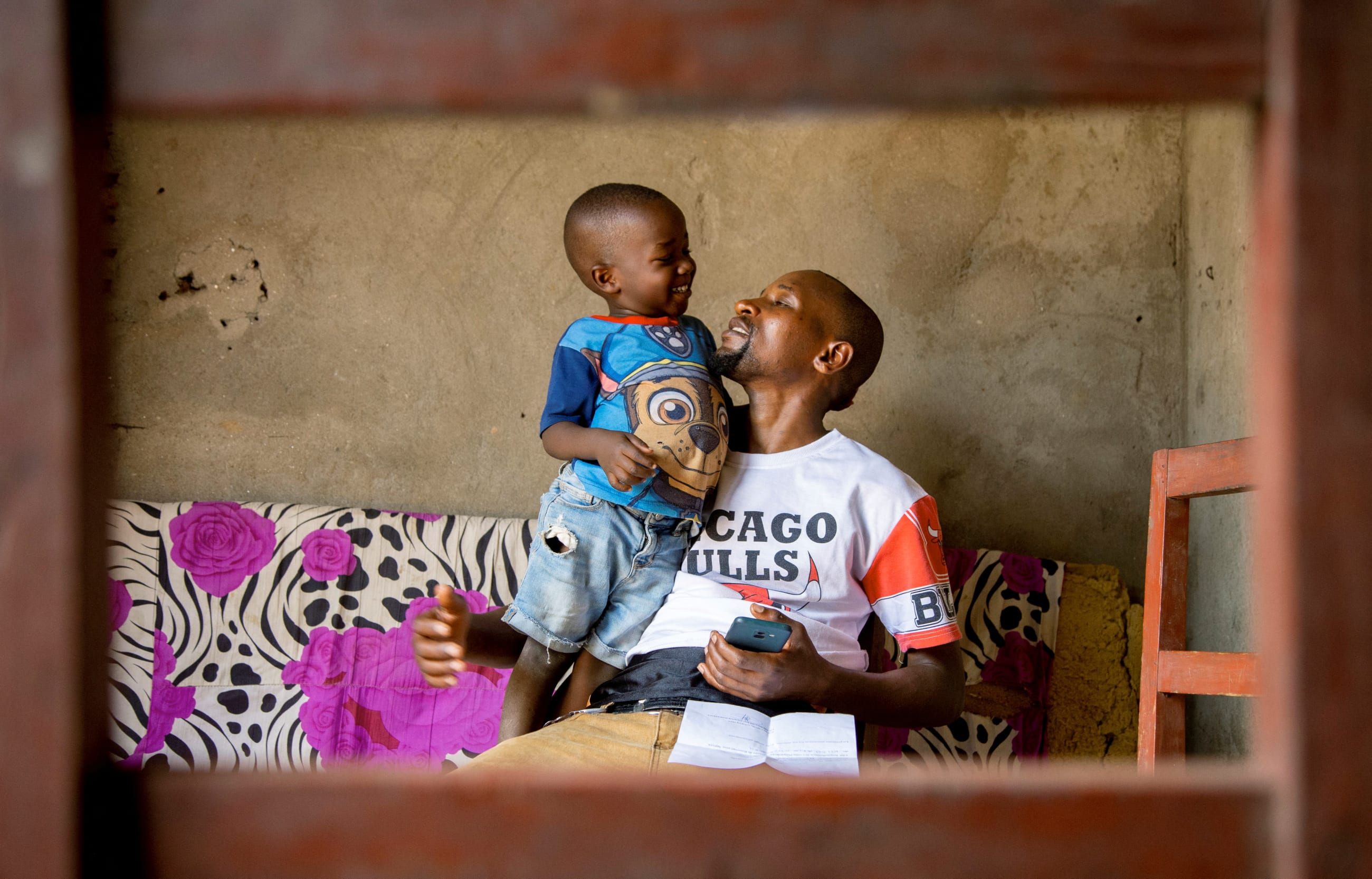 Manigaba Eric, plays with his son in their home after returning from the mpox treatment center.