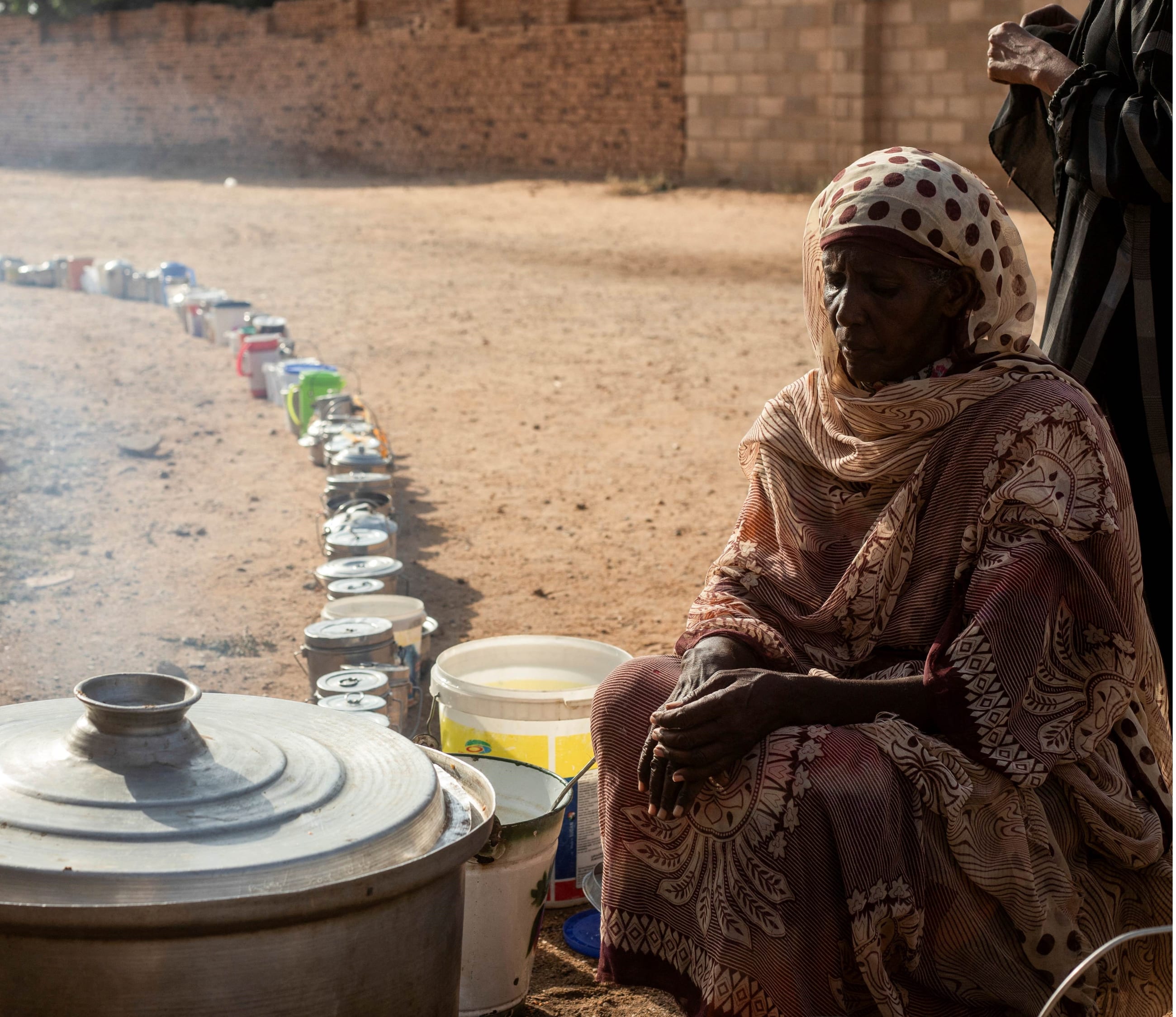 A Sudanese woman from a community kitchen, run by local volunteers as empty pots are seen lined up to receive food, in Omdurman, Sudan, on September 19, 2024.