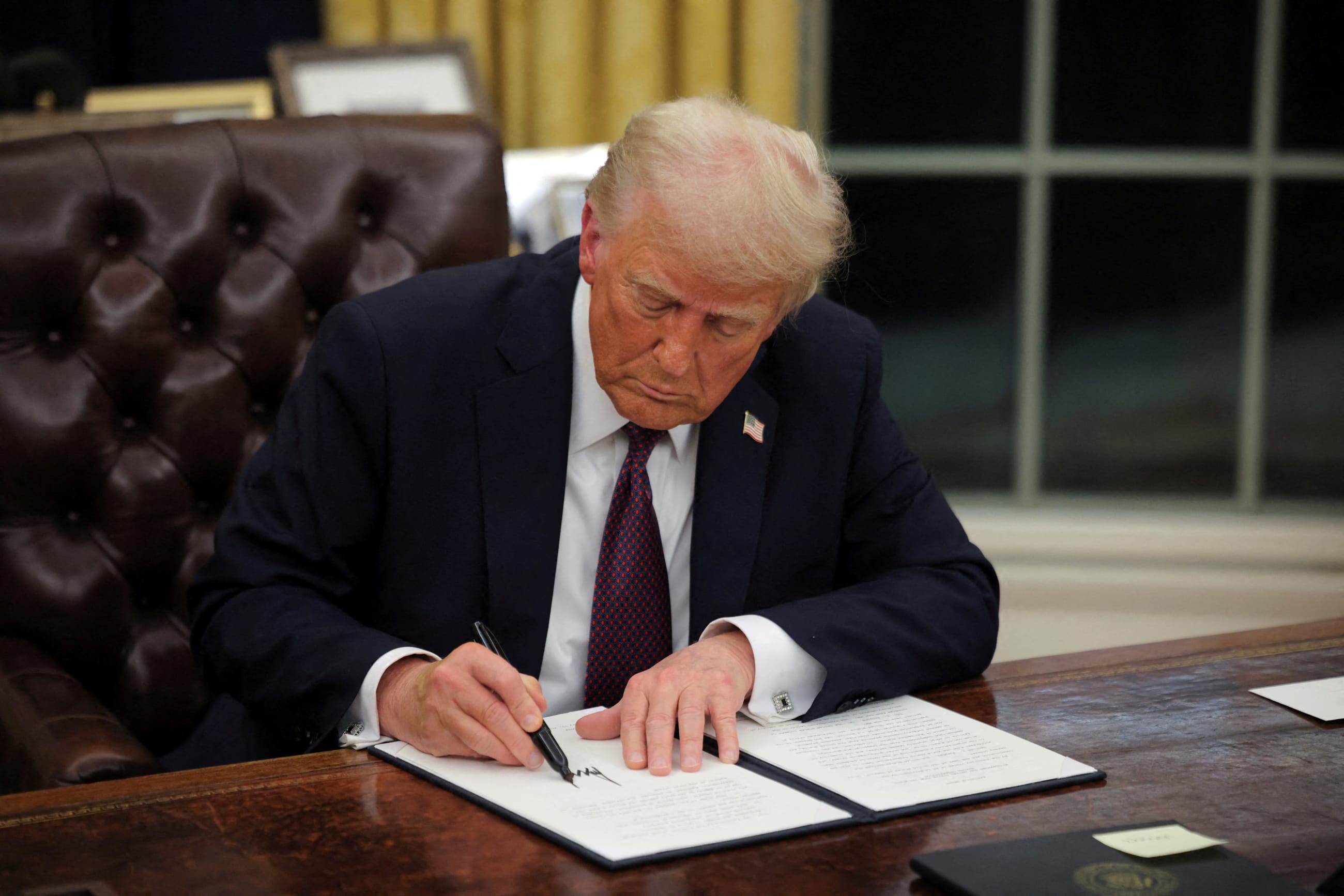 U.S. President Donald Trump signs documents as he issues executive orders and pardons in the Oval Office at the White House, on Inauguration Day, in Washington, DC, on January 20, 2025.