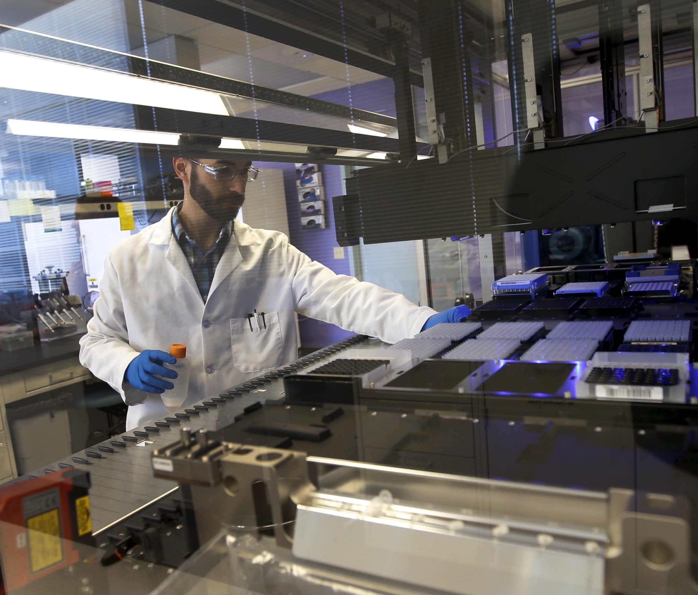 A technician loads a robotic DNA sample automation machine, at a Regeneron Pharmaceuticals Inc. Laboratory, in Tarrytown, New York, on March 24, 2015.