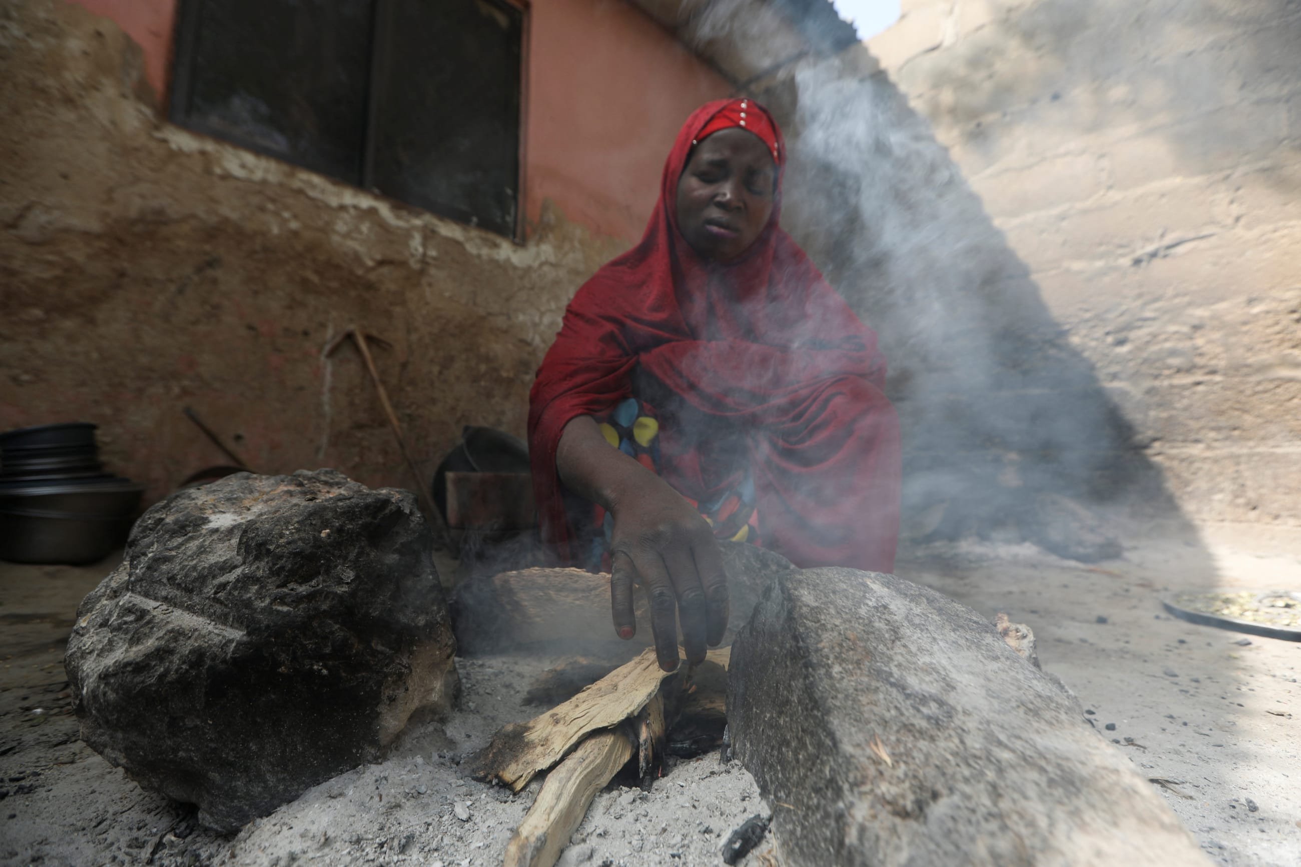 A Nigerian woman who fled attacks by bandits in her village, makes a fire with wood at a makeshift kitchen, in a shelter for displaced people, in Gusau, Zamfara, Nigeria, on February 8, 2023.
