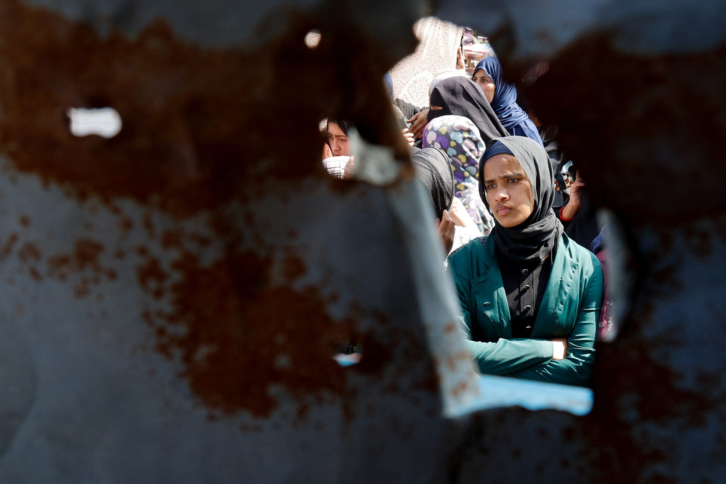 A Palestinian woman looks on as she and others gather to receive bread from a bakery, in Khan Younis, Gaza Strip, on March 9, 2025.