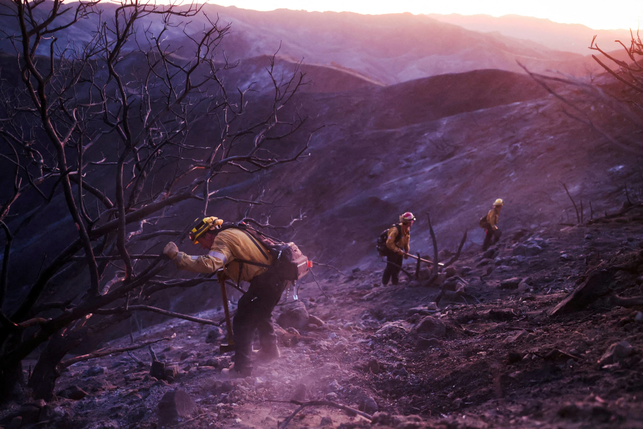 Members of a CalFire crew work to mop up hotspots from the burn scar of the Palisades Fire near Mulholland Drive in Los Angeles, California, U.S., January 15, 2025.