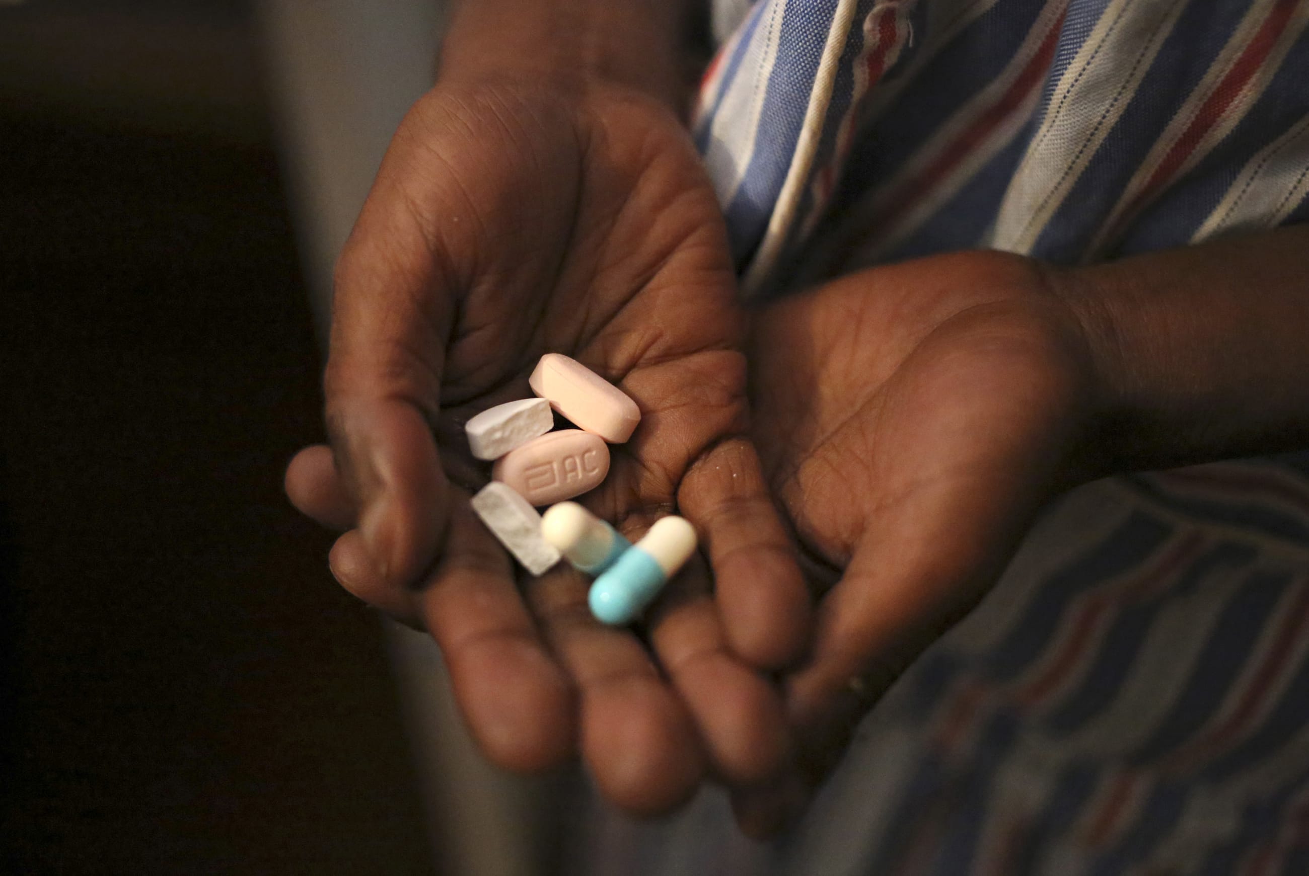 A boy holds a handful of antiretroviral pills before taking his medication at Nkosi's Haven, in Johannesburg, South Africa, on November 28, 2014.