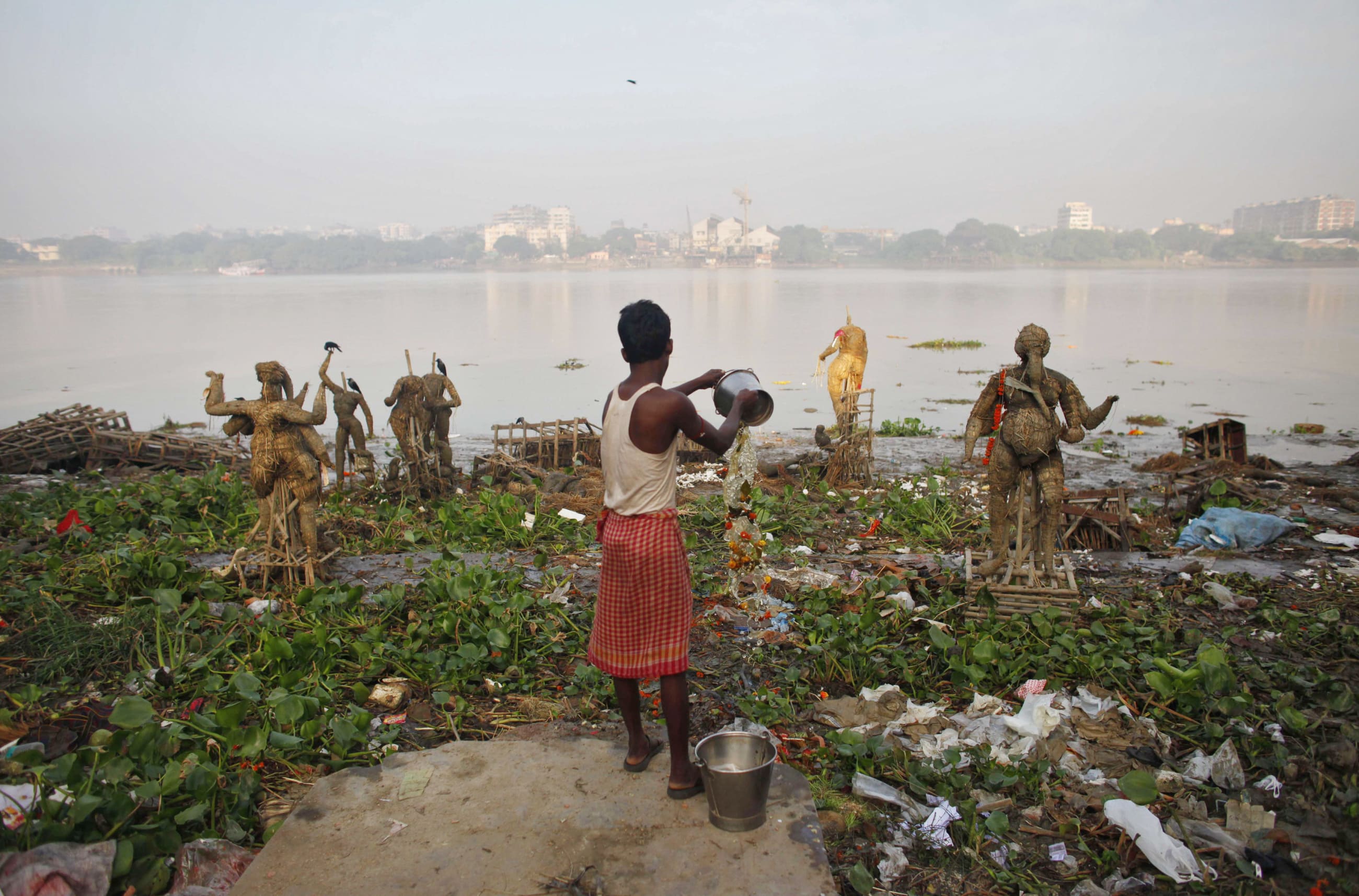 A man pours water on the polluted banks of river Ganges, in Kolkata, India, on October 20, 2010. 