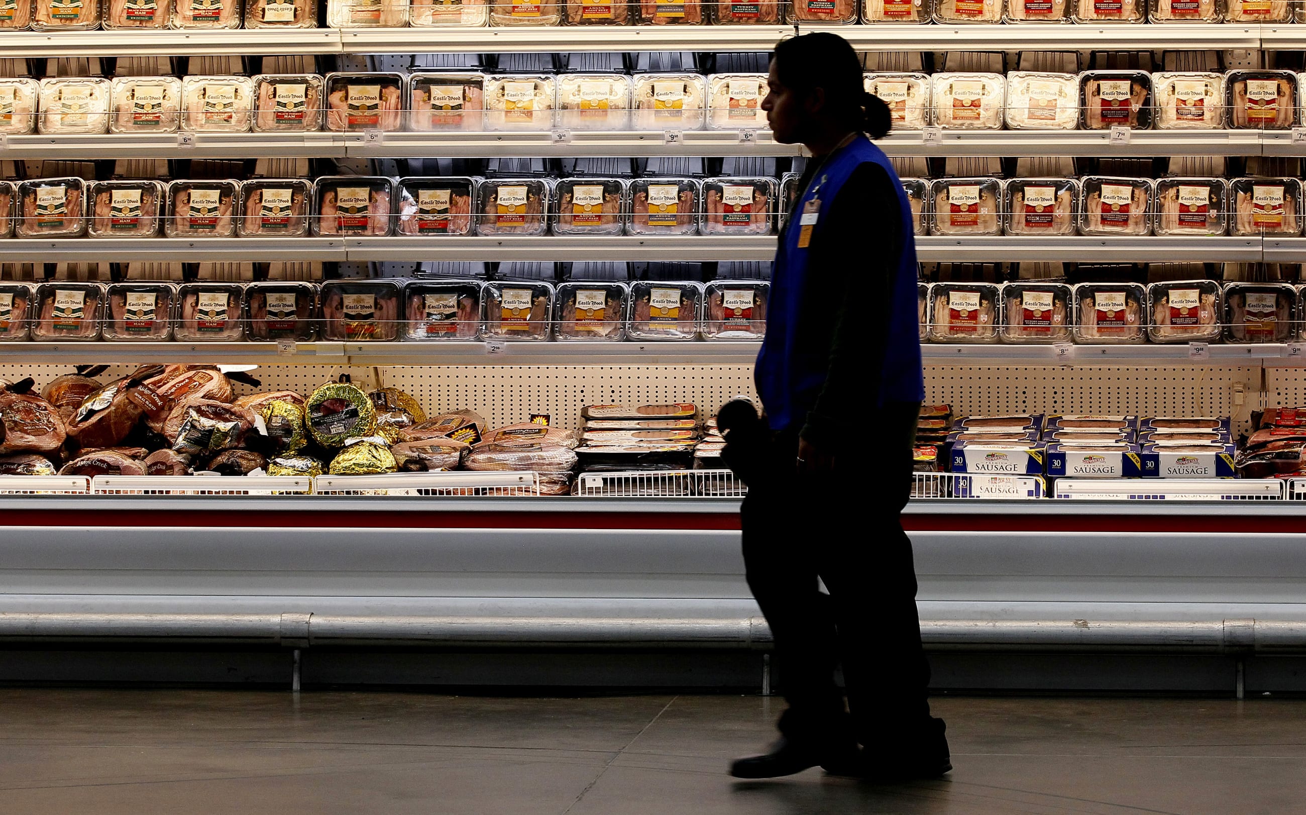A employee walks by a meat cooler in the grocery section of a Sam's Club, in Bentonville, Arkansas, on June 5, 2014.