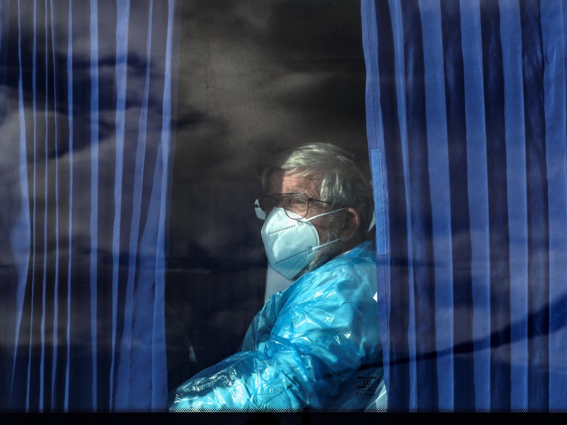 A passenger of the cruise ship MV Hondius, affected by a hantavirus outbreak, looks on from inside a bus as it leaves the port of Granadilla de Abona, in Tenerife, Spain, on May 11, 2026.