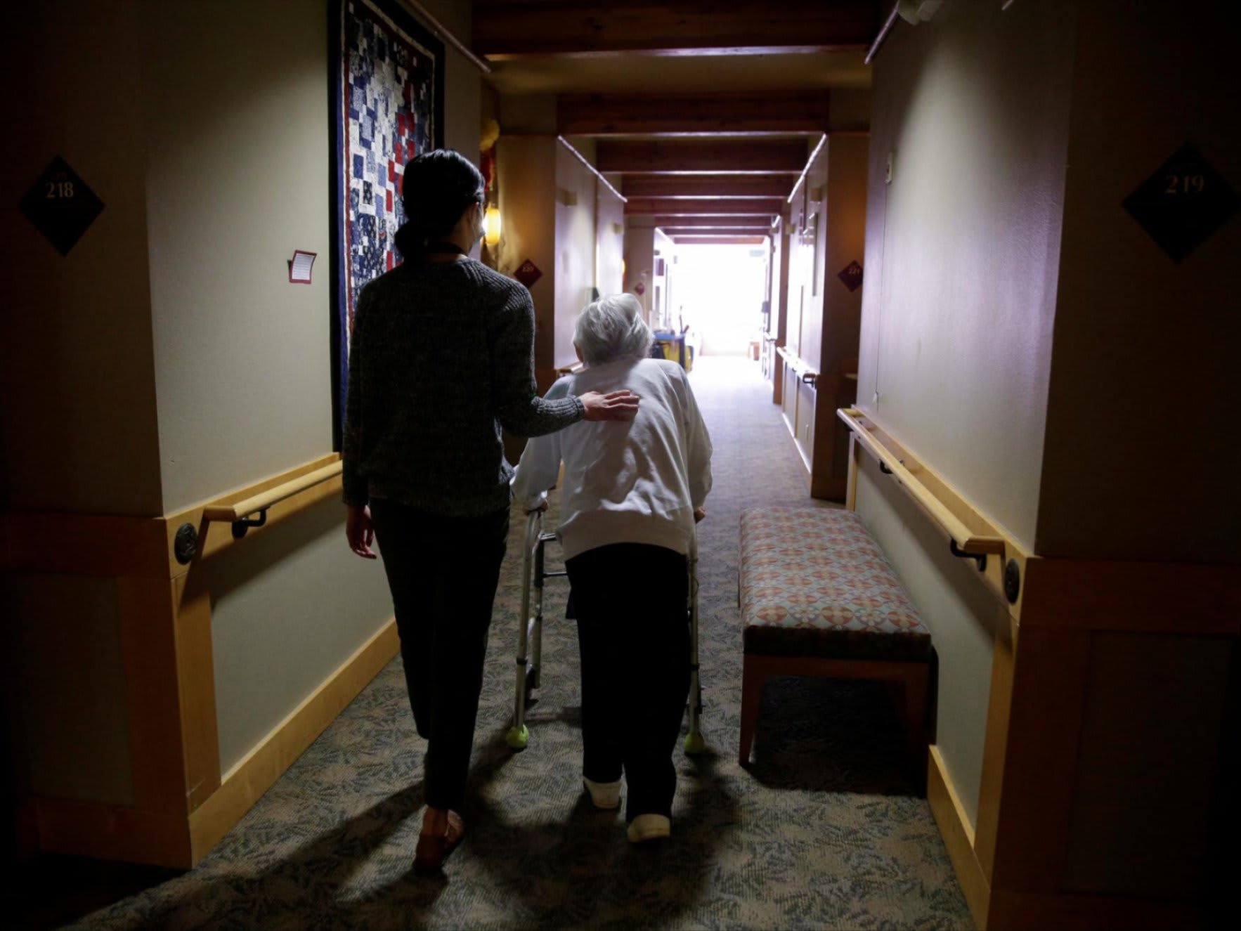 An elderly woman is guided back to her room for a family visit at Nikkei Manor, an assisted living facility, in Seattle, Washington, on March 30, 2021.