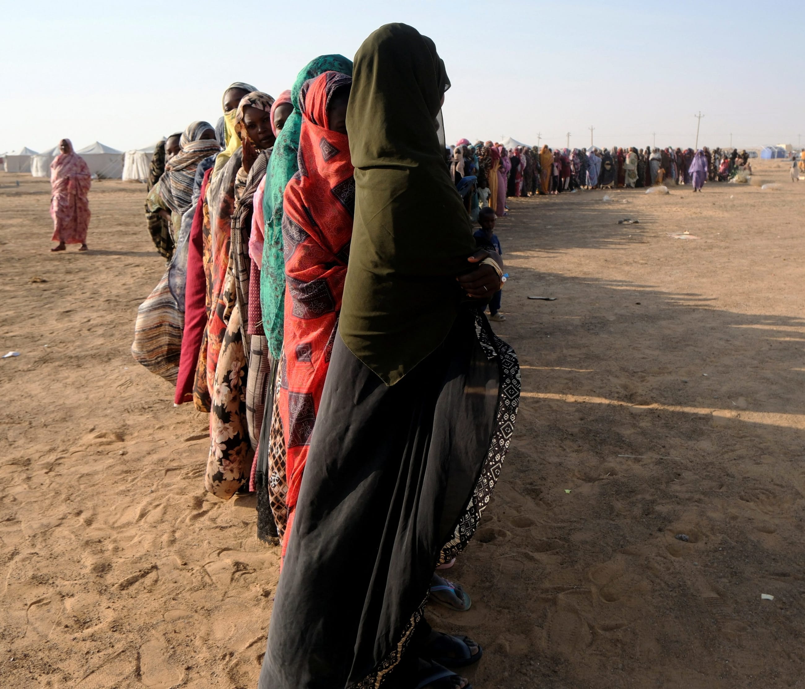 Displaced women stand in a long queue to receive food supplies at a displacement camp, in Al-Dabbah, Sudan, on November 13, 2025.