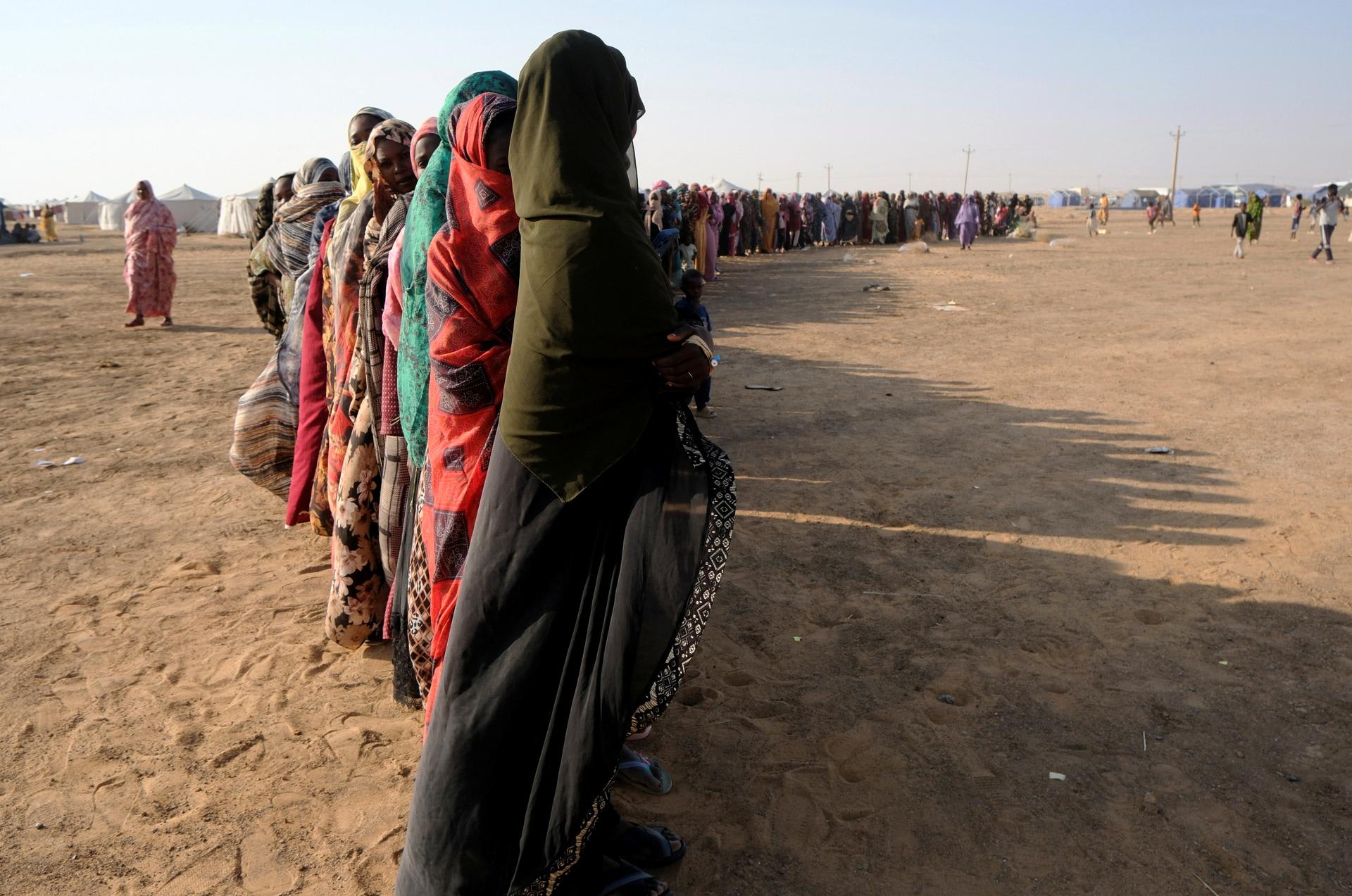 Displaced women stand in a long queue to receive food supplies at a displacement camp, in Al-Dabbah, Sudan, on November 13, 2025.