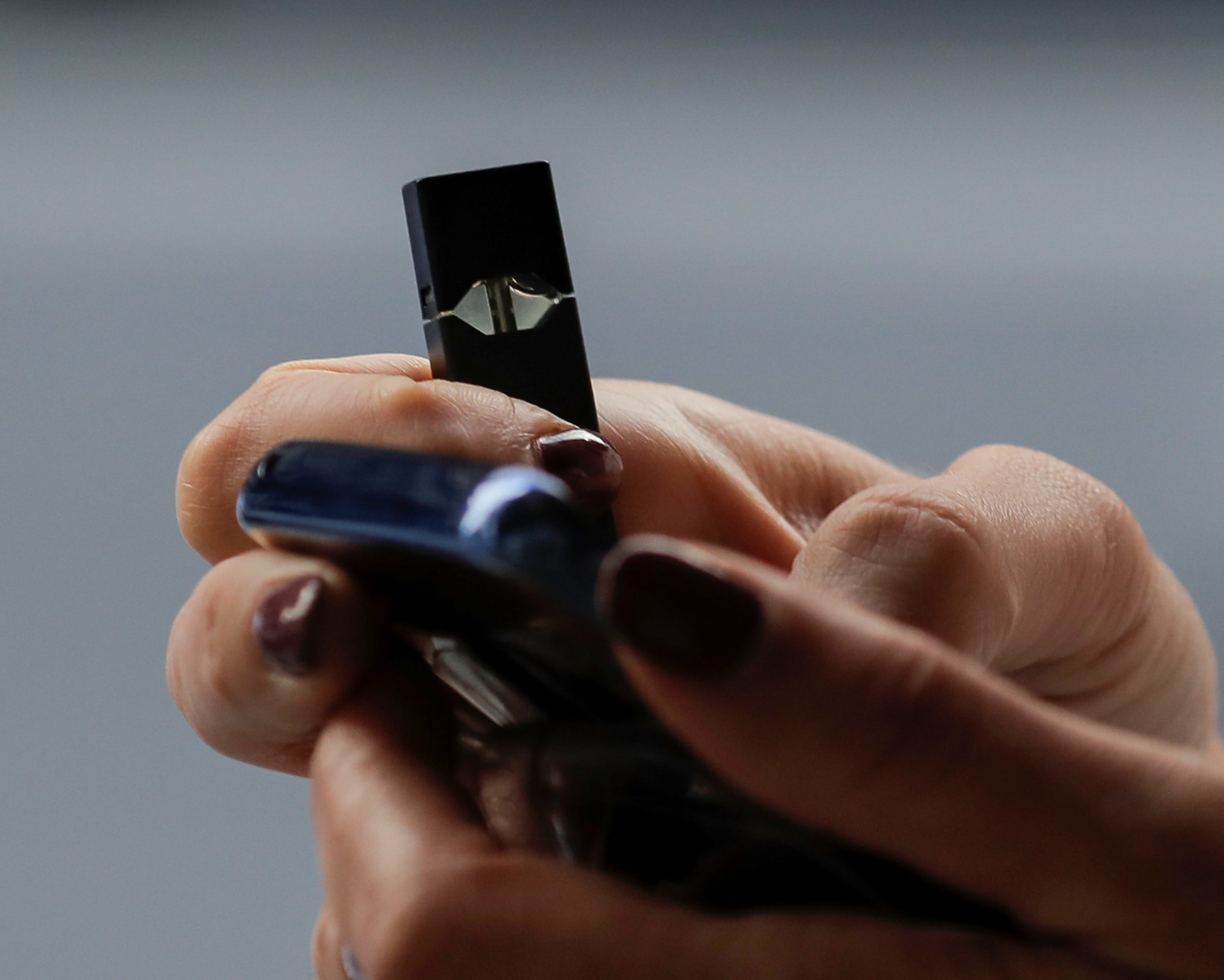 A woman holds a Juul e-cigarette while walking, in New York, on September 27, 2018.