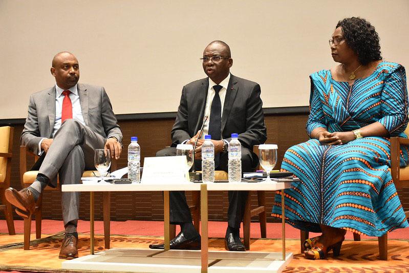 The image shows the three former ministers witting in lounge chairs having a panel discussion on a stage.