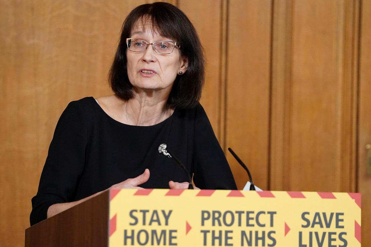 The image shows the medical officer at a podium speaking into a microphone.