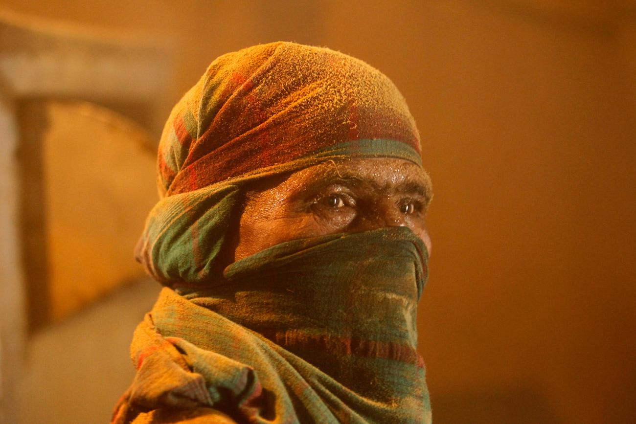 Picture shows the covered face of a woman in an orange glowing light.