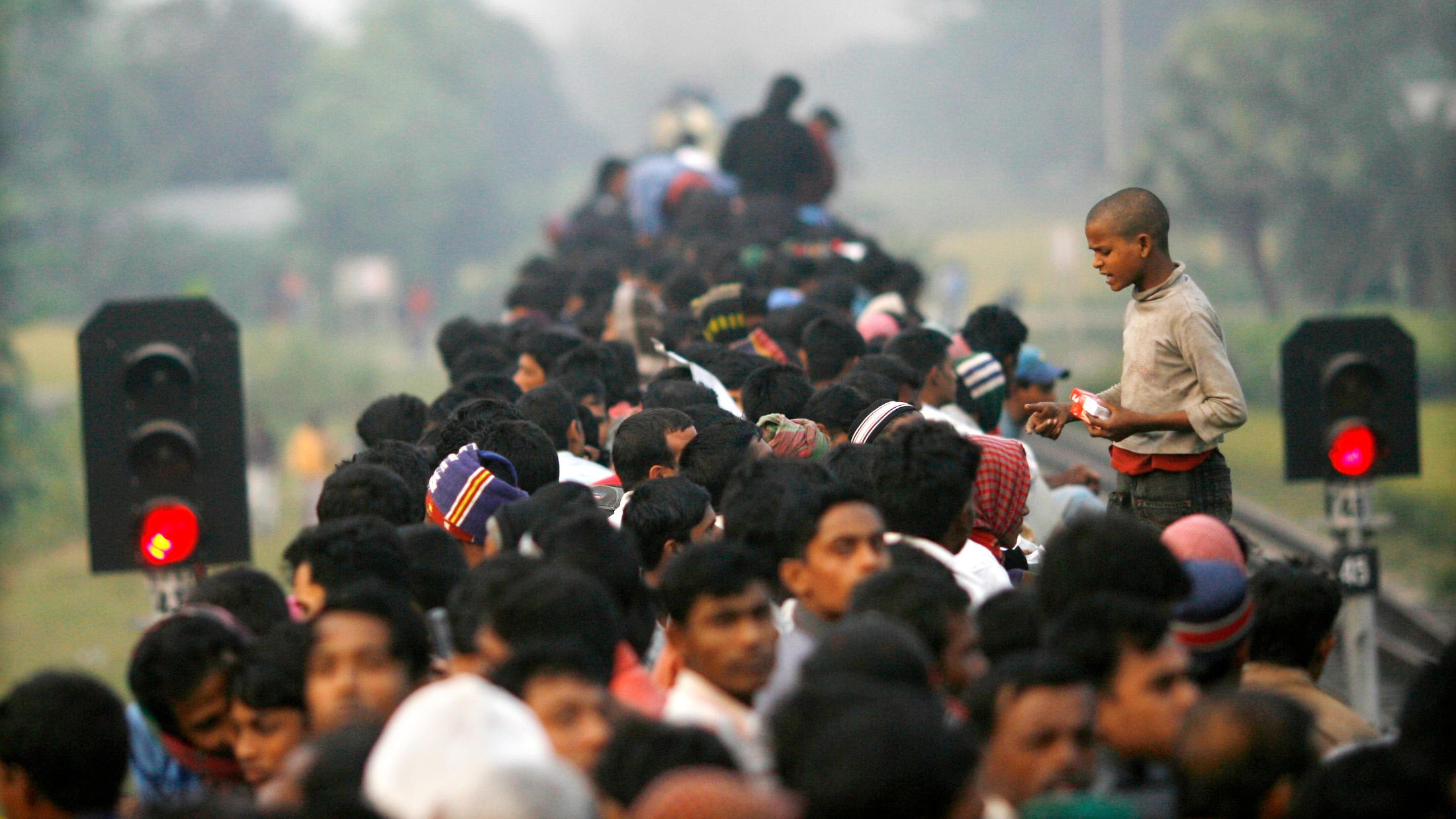 The photo shows a boy standing above a crowd of seated adults hawking smokes.