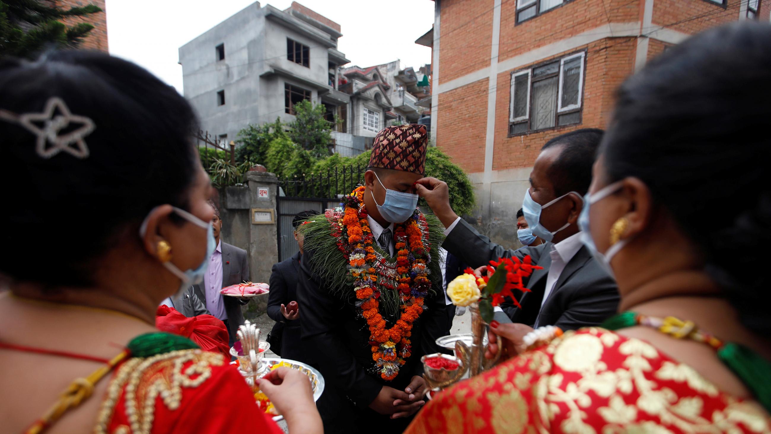 The photo shows the groom participating in the ceremony with an official touching his head.