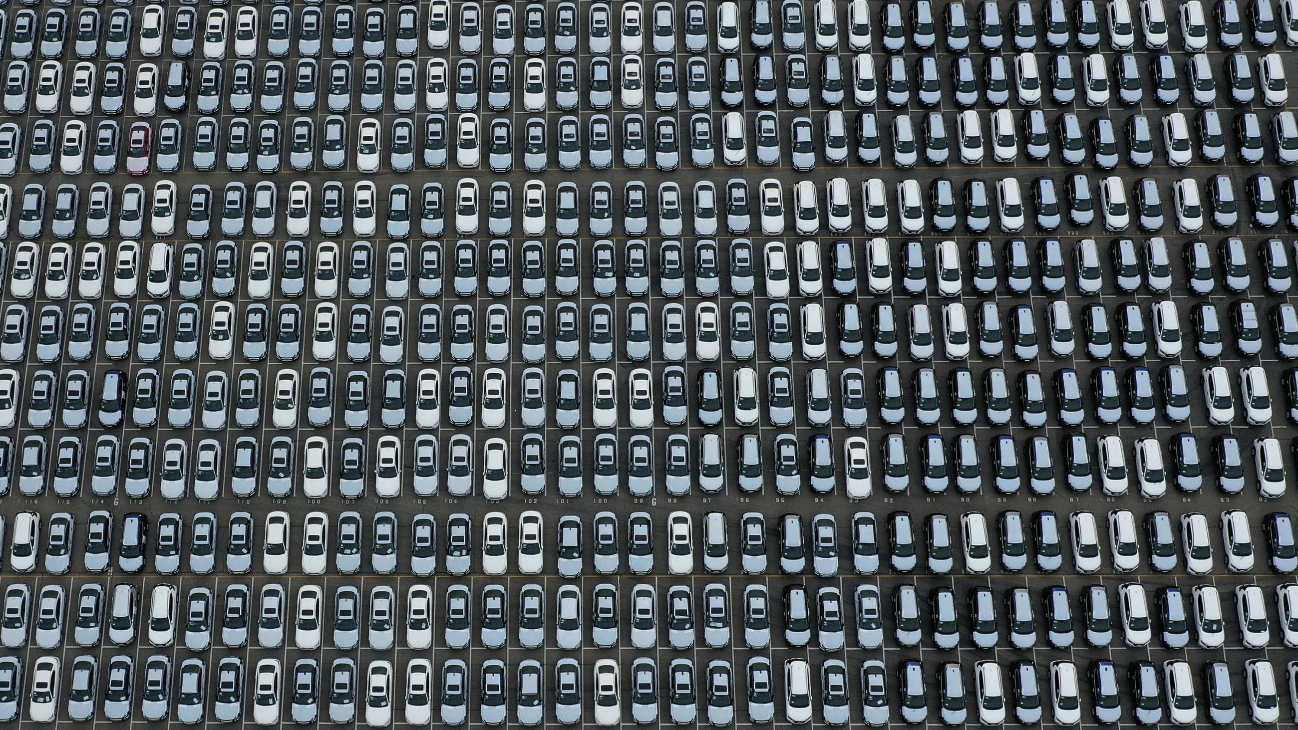 The photo is an aerial shot of a large lot packed completely with lines of cars.