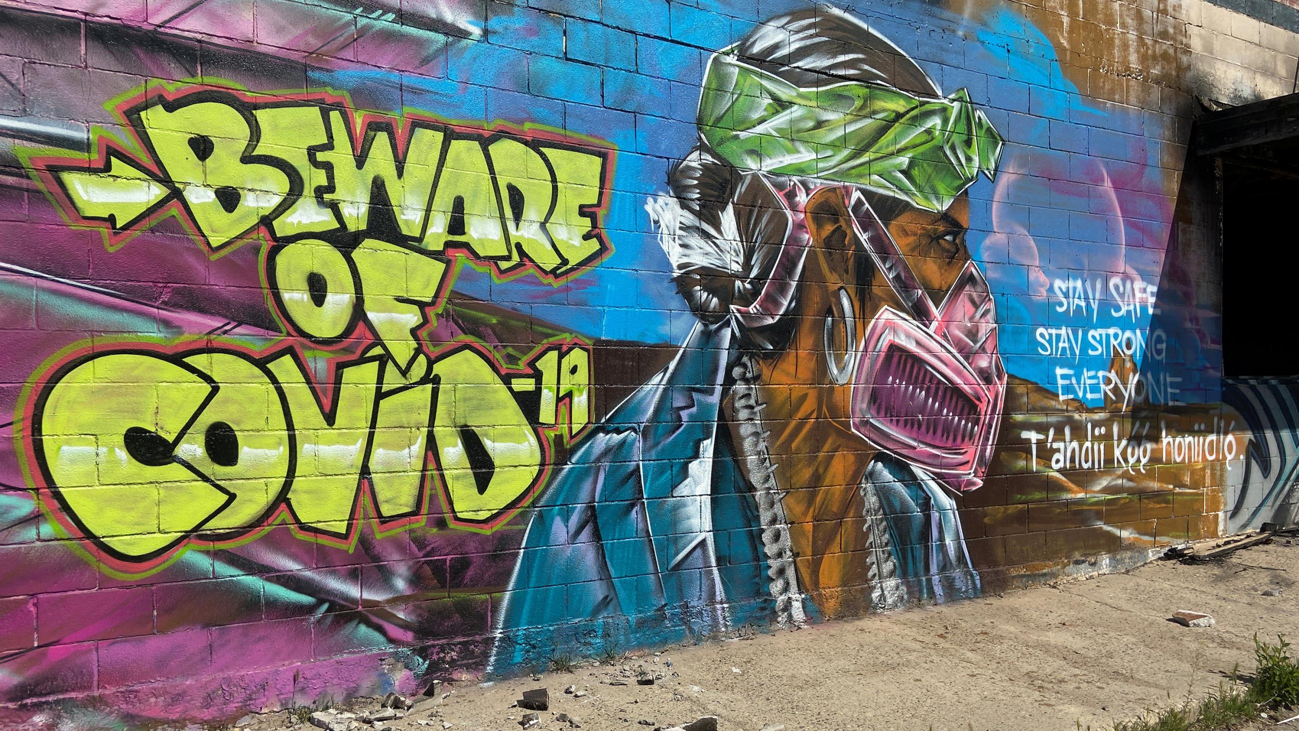 Picture shows an amazing mural of a man wearing a mask painted on the side of a wall.