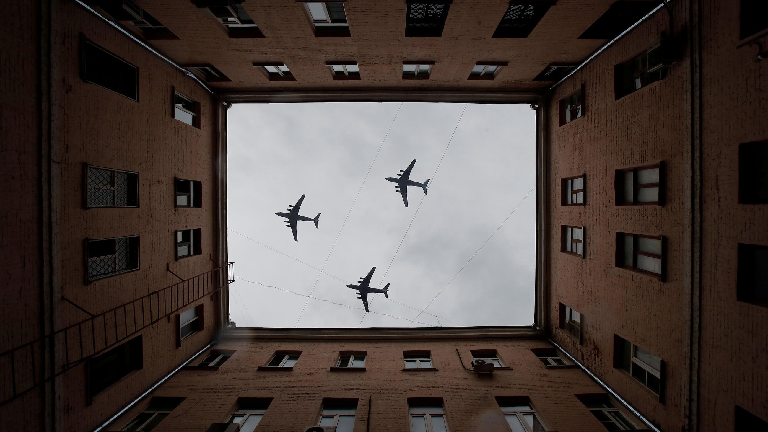 The striking image shows three planes photographed looking up througg the open courtyard of a large apartment-style building.