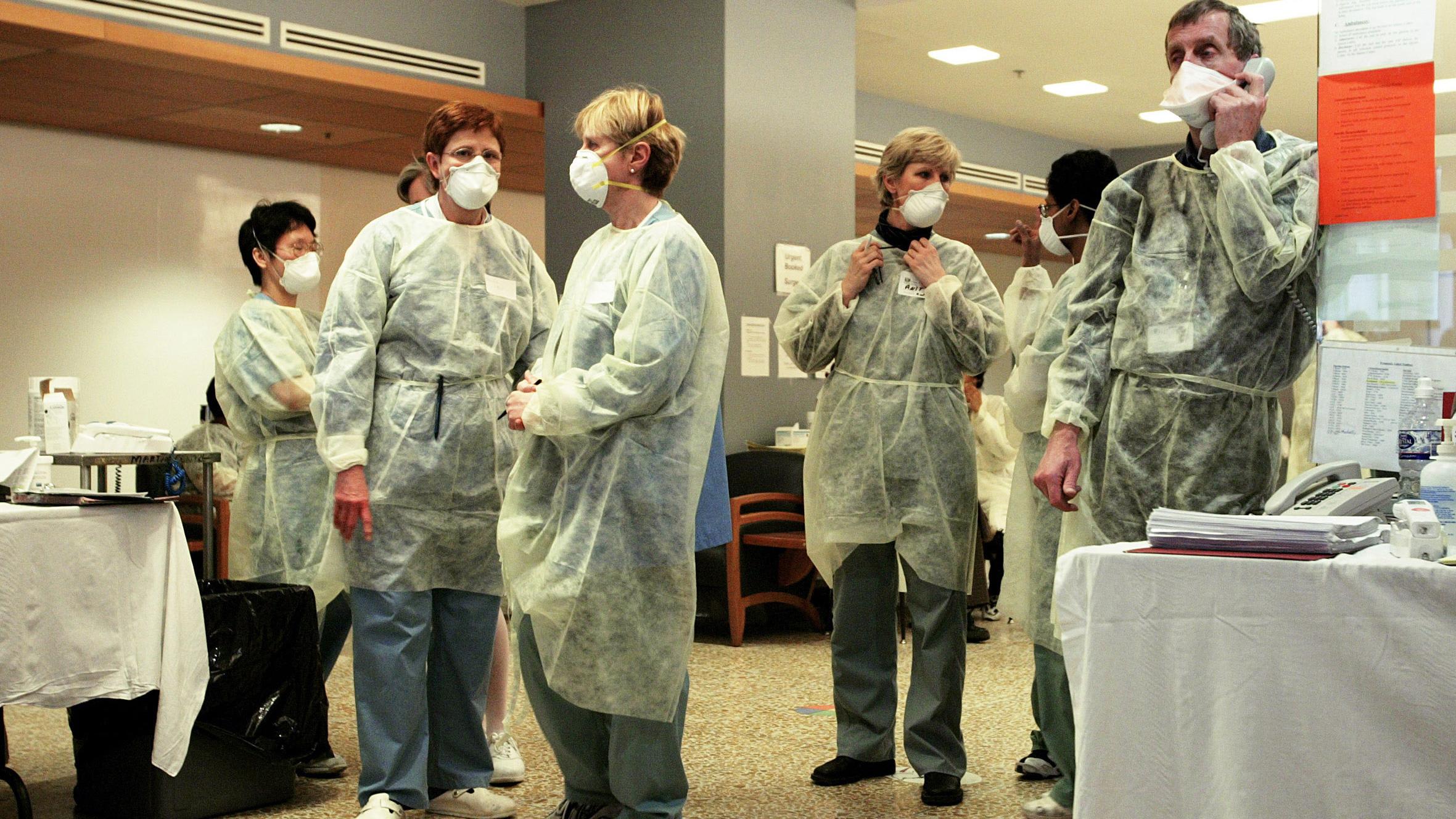 The photo shows a number of hospital staff waiting and talking amongst themselves. One is on the phone.
