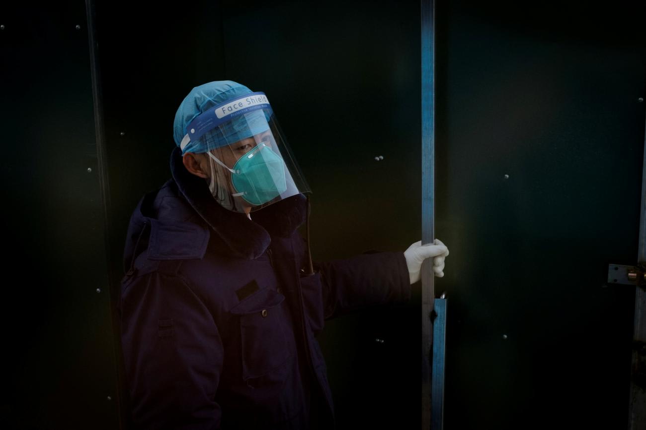 A security guard wearing a mask and a shield as protection against COVID opens a gate at a hotel inside the closed loop at the 2022 Winter Olympics in Beijing, China, on February 1, 2022.