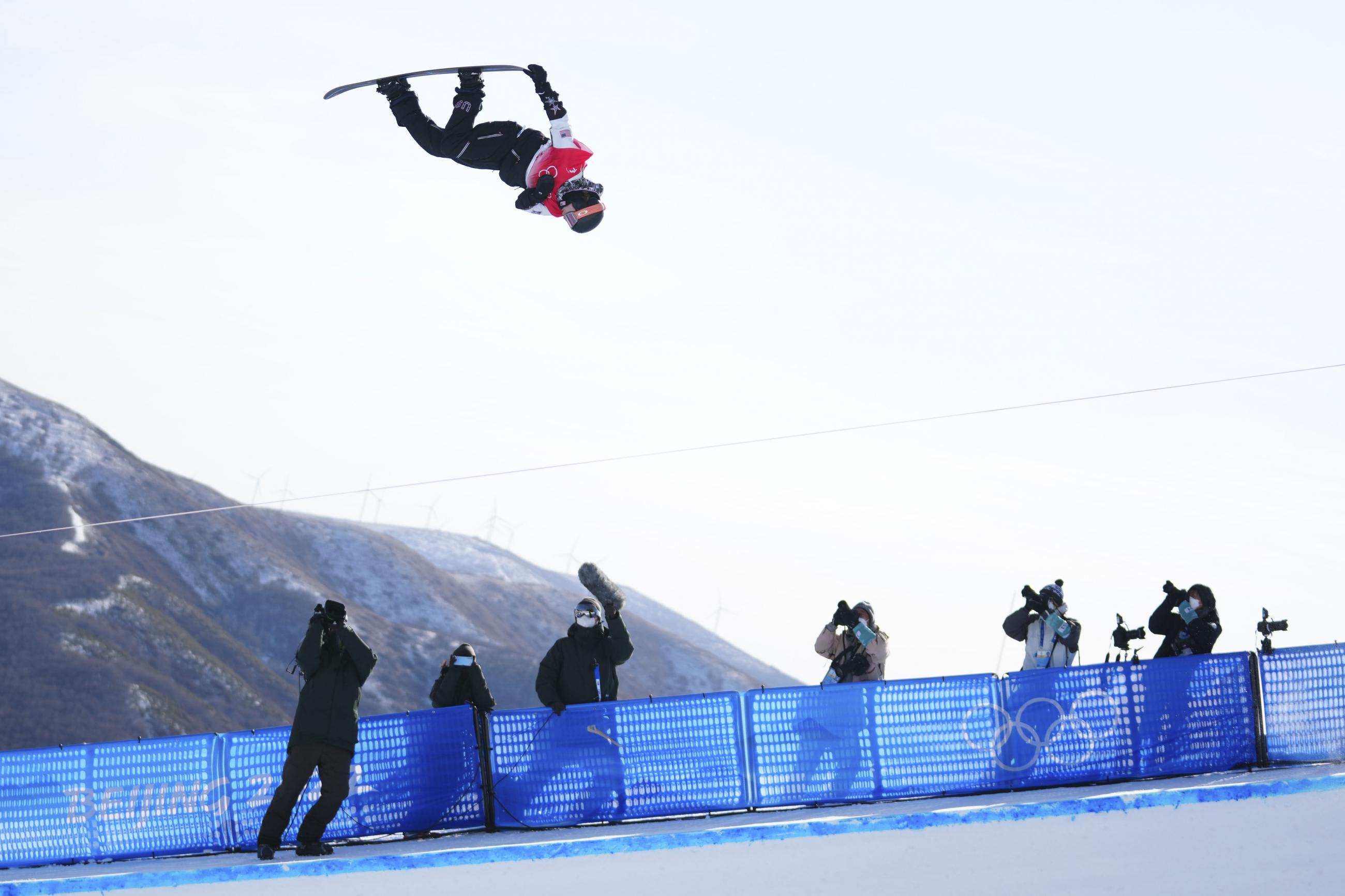 Taylor Gold (USA) goes airborne as photographers in masks shoot photos from below during the snowboard mens halfpipe final at the Beijing 2022 Olympic Winter Games at Genting Snow Park.