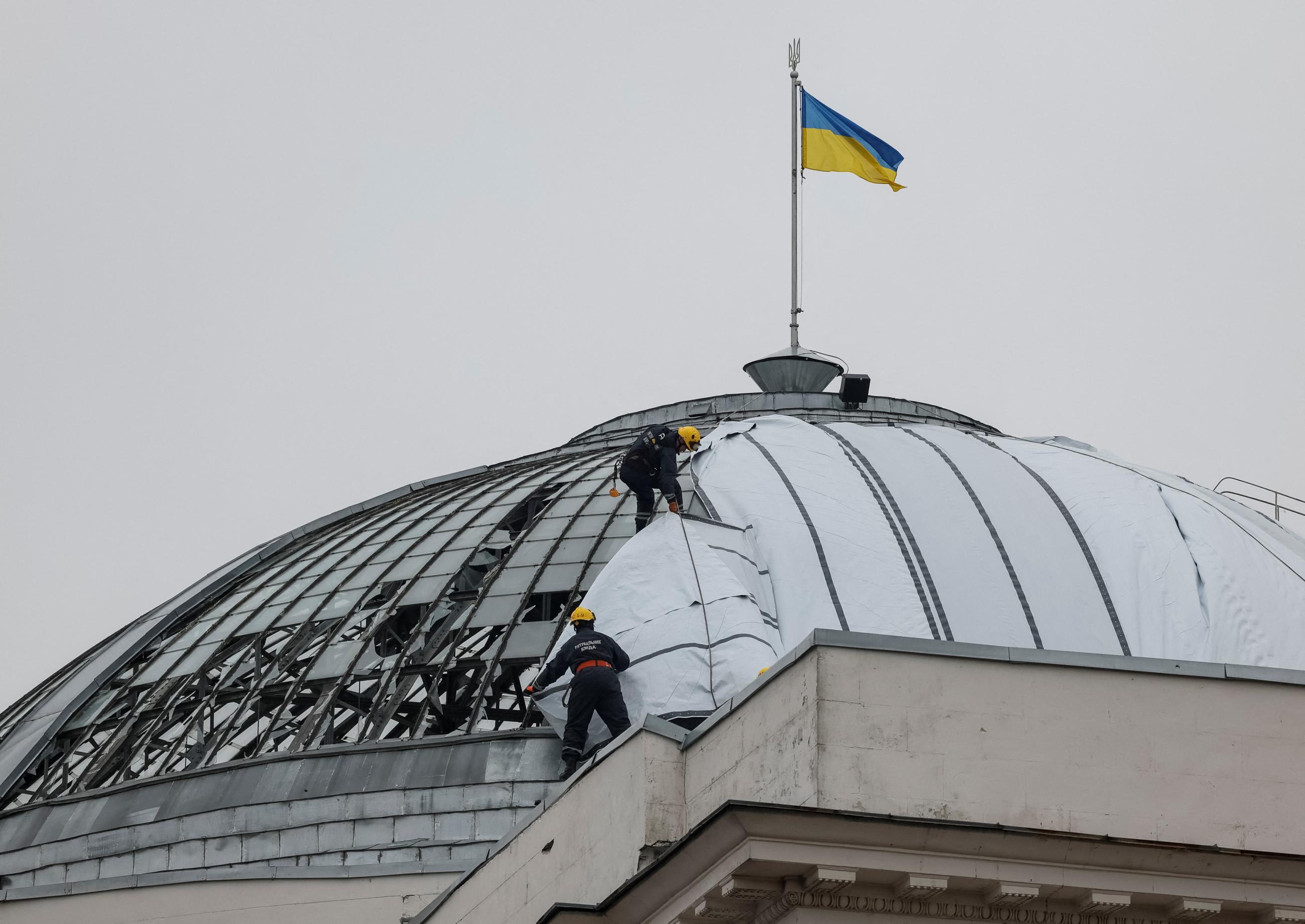 Climbers cover a glass roof as they stand atop an historic building damaged by a Russian missile strike, as Russia's invasion of Ukraine continues, in the center Kyiv, Ukraine, on October 20, 2022. REUTERS/Gleb Garanich