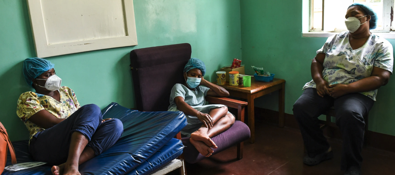 Three exhausted health workers rest on chairs and a couch during the January 2021 surge of COVID-19 at Queen Elizabeth Central Hospital in Blantyre, Malawi.