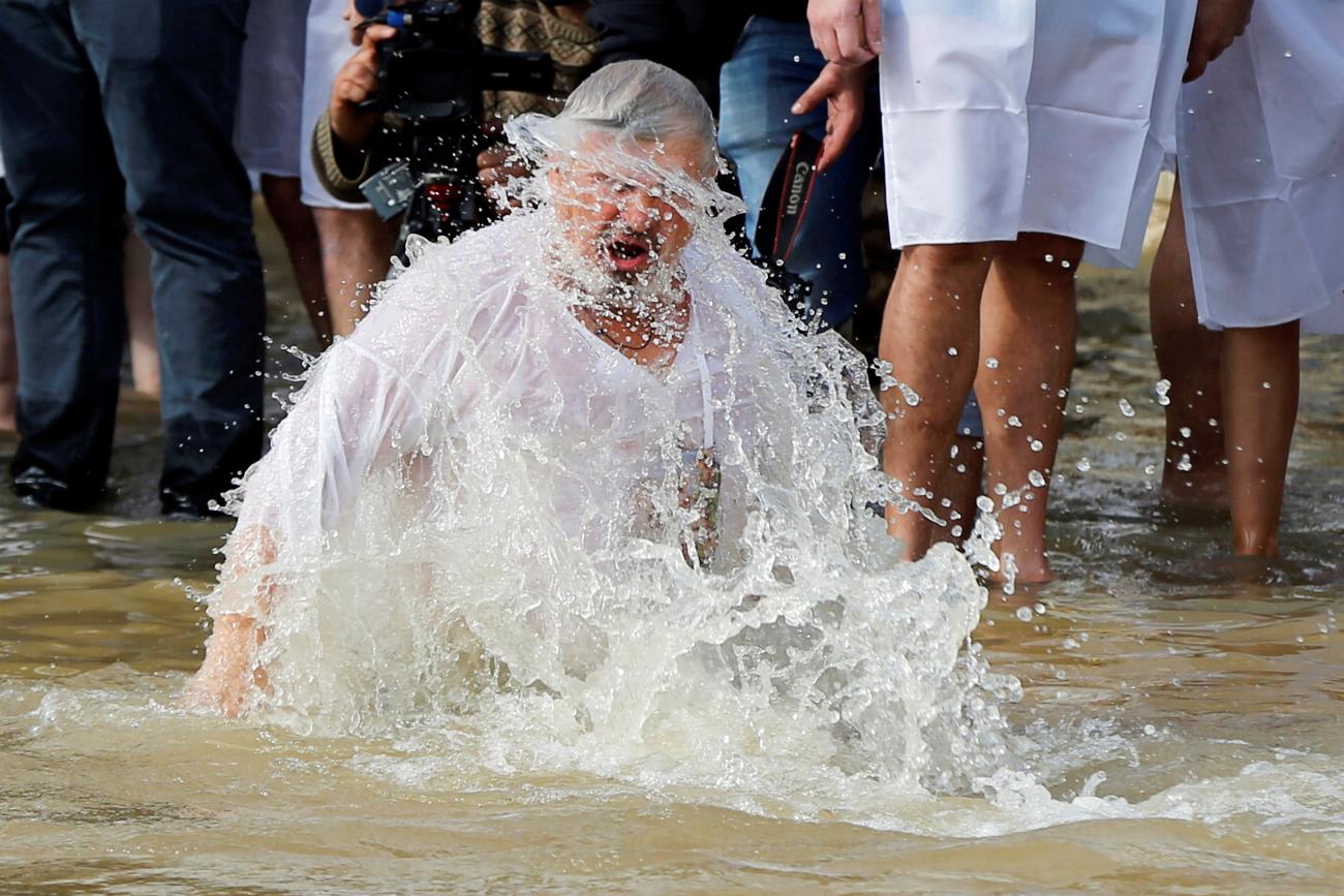 A pilgrim takes a dip in the waters of the Jordan River during a baptism ceremony at the Qasr el-Yahud site, near Jericho, in the Israeli-occupied West Bank as seen from the East Bank, Jordan January 18, 2019.