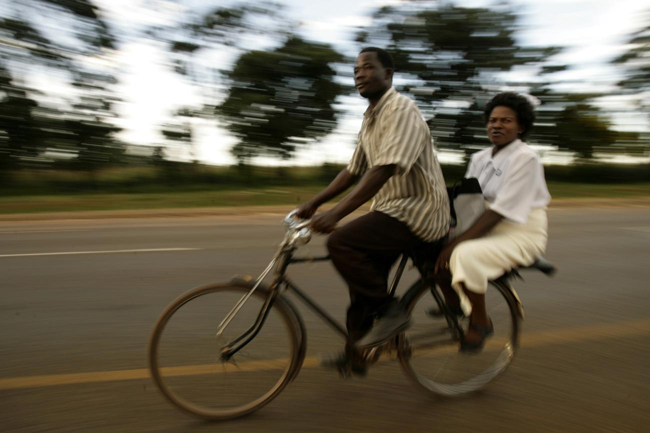 A nurse (right) returns from work on a bicycle along the Mchinji road-the highway linking Malawi to Zambia’s eastern province on April 21, 2008.