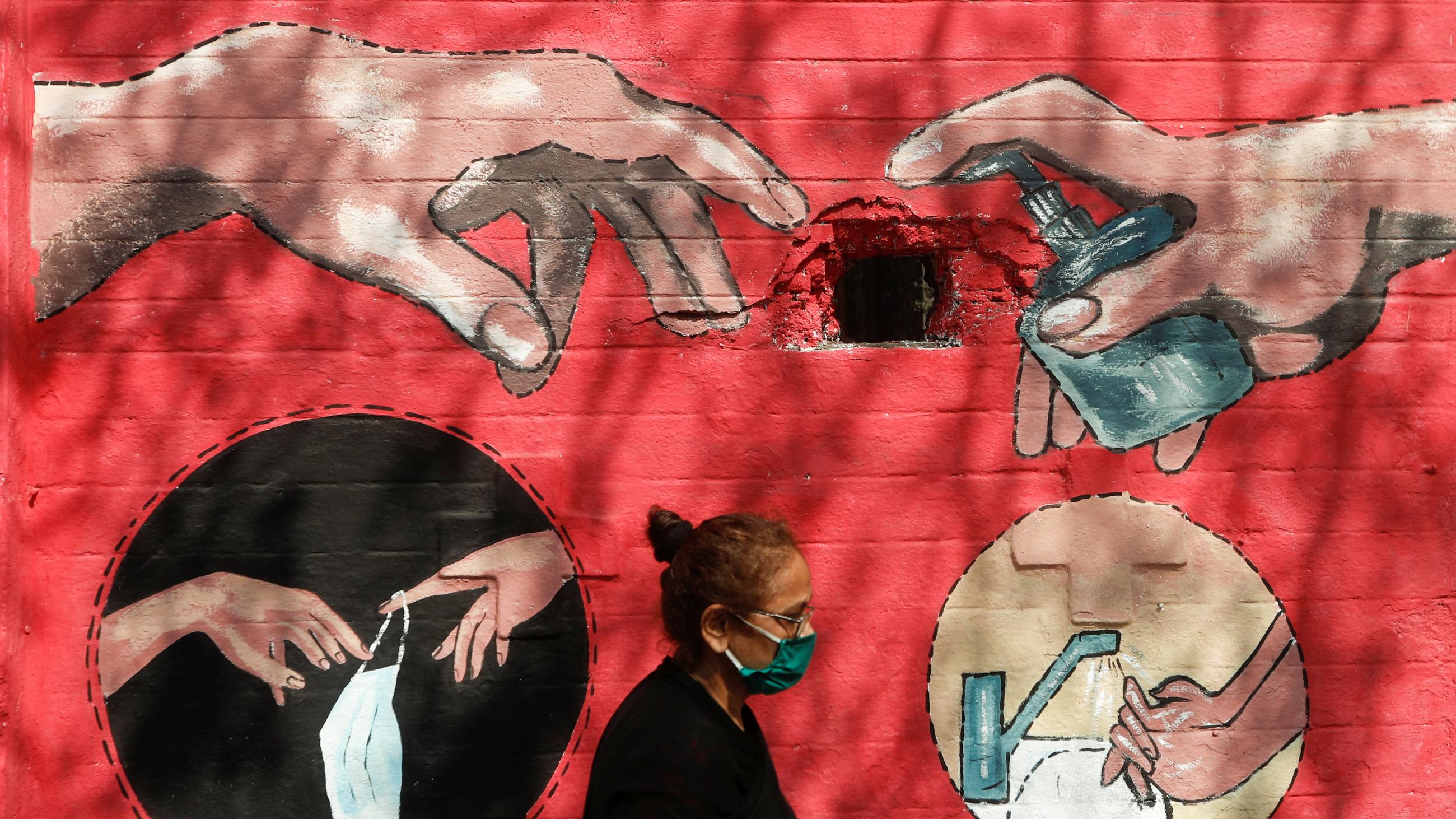 Street art encouraging hand washing, and the use of masks and hand sanitizer mimics Michelangelo’s Creation of Adam, in Mumbai, India, on April 6, 2021.