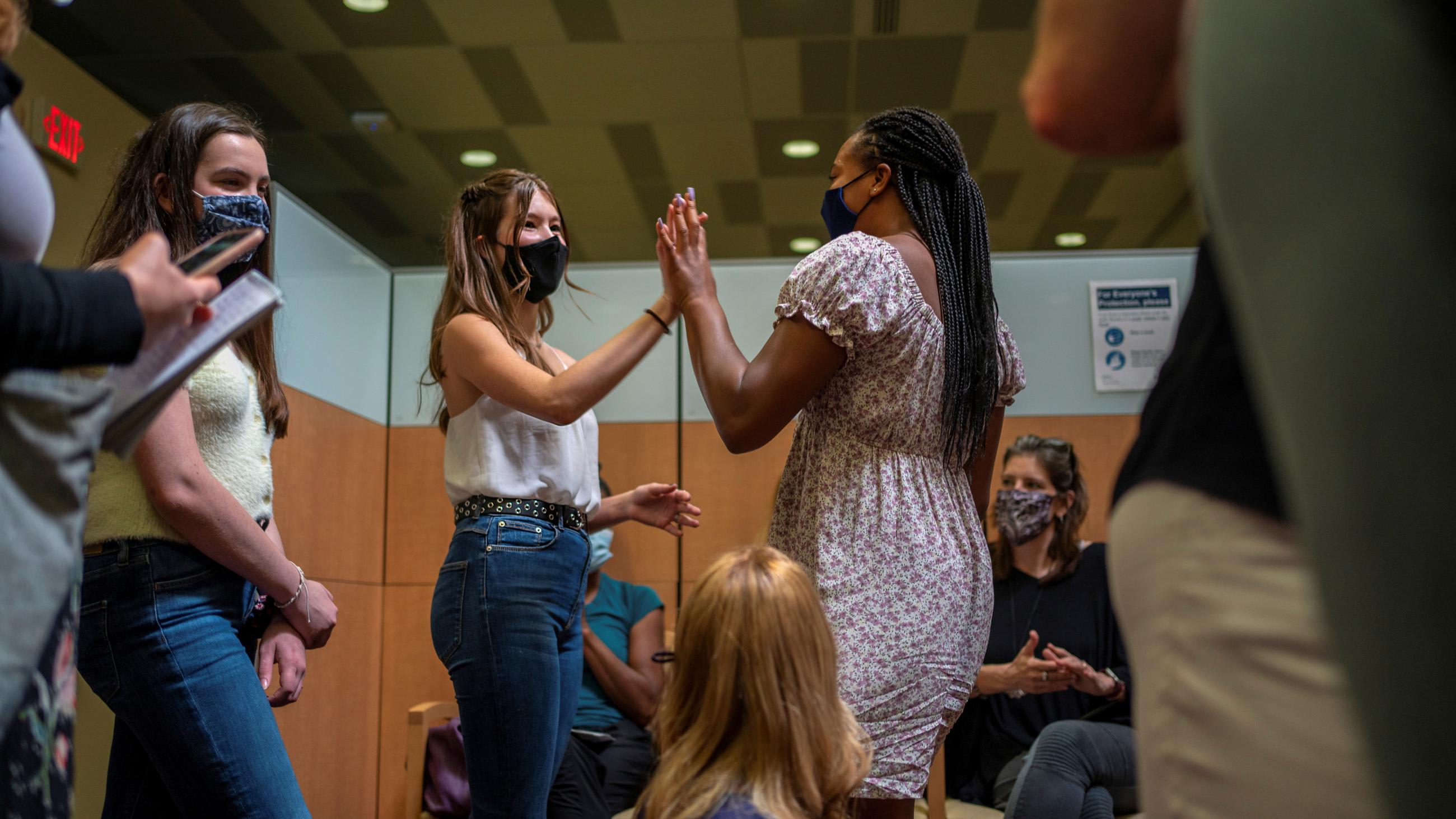 Teens high five after Croix received her first COVID vaccine at the Ochsner Center for Primary Care and Wellness, in New Orleans, Louisiana, May 13, 2021.