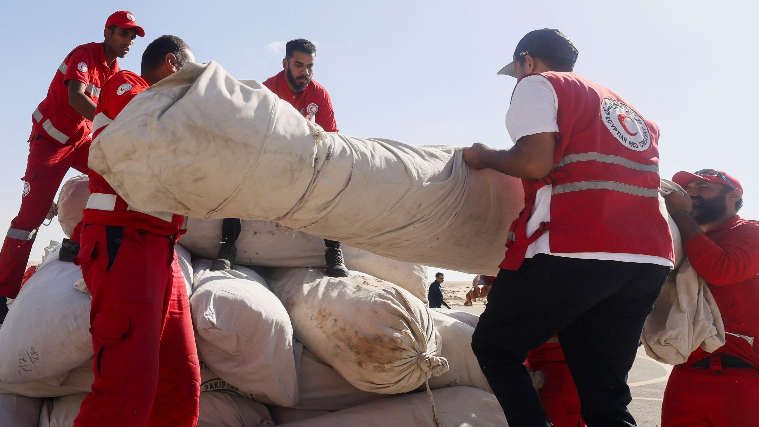 Five men seen loading a truck with large object wrapped in a white sheet.