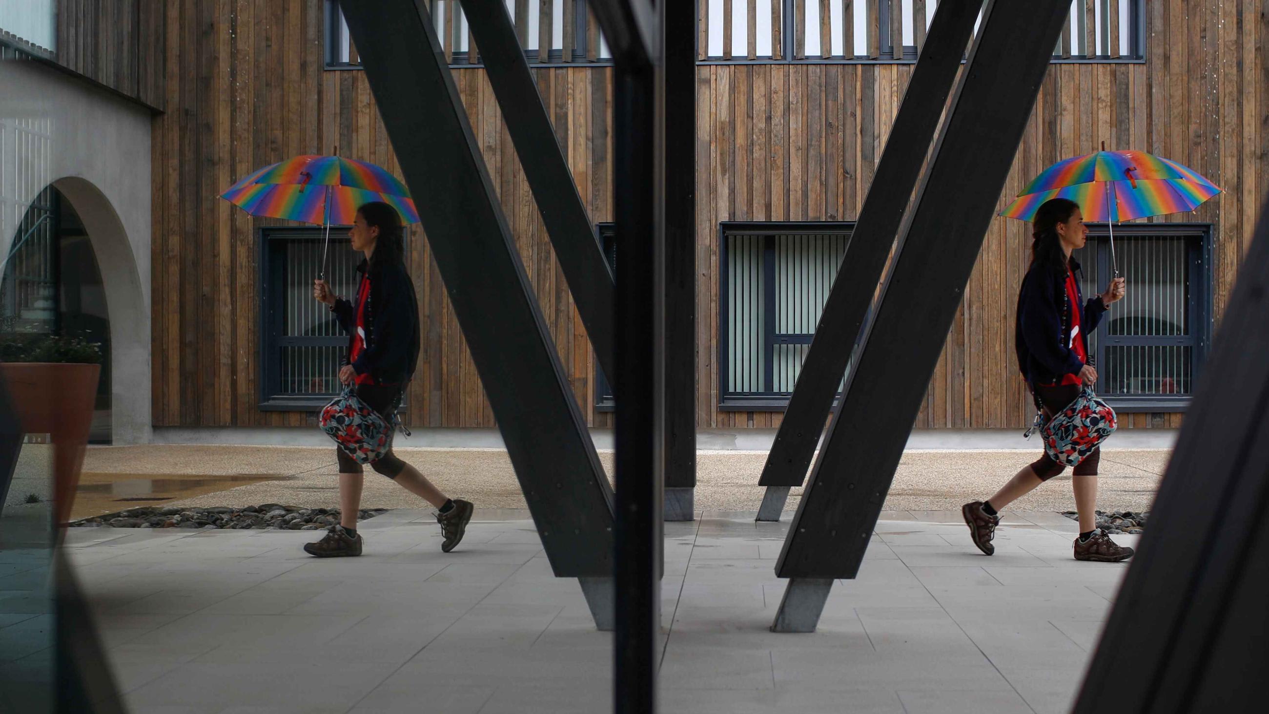 Alzheimer’s patient Laetitia, thirty-nine, is reflected in a mirror as she walks with an umbrella at the Village Landais Alzheimer site in Dax, France, on September 24, 2020.