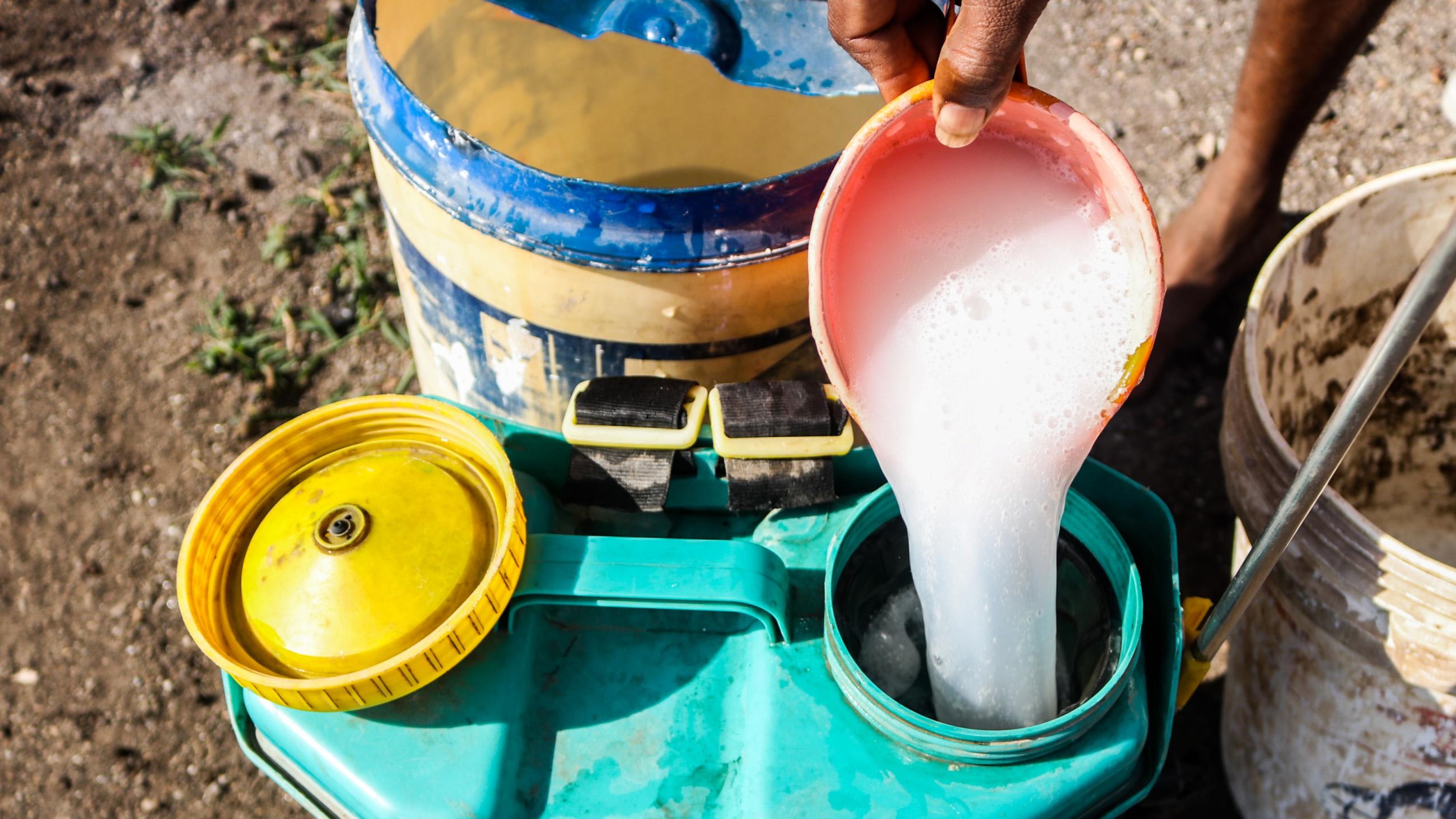 A farmer preparing a mixture of potent chemical pesticides to protect his vegetables.