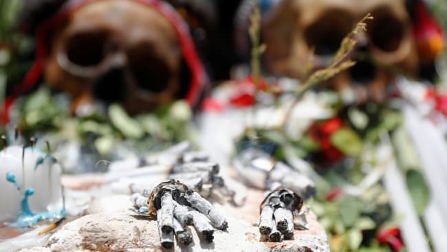 Cigarette butts are seen in front of exhibited skulls during the Day of Skulls celebrations in La Paz, Bolivia November 8, 2019. The photo shows two human skulls laid out with flowers in a ceremonial way with a number of burned cigarettes in the foreground. REUTERS/Kai Pfaffenbach